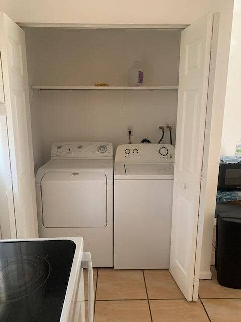 933 Francis Street, West Palm Beach, FL 33405 Dedicated laundry closet featuring a washer and dryer, bifold doors, and a built-in storage shelf