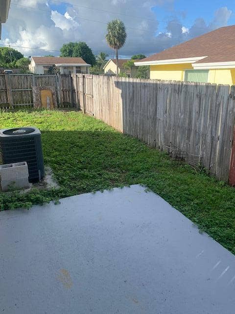 933 Francis Street, West Palm Beach, FL 33405 Expansive backyard featuring a concrete patio, grassy lawn, and wood privacy fencing