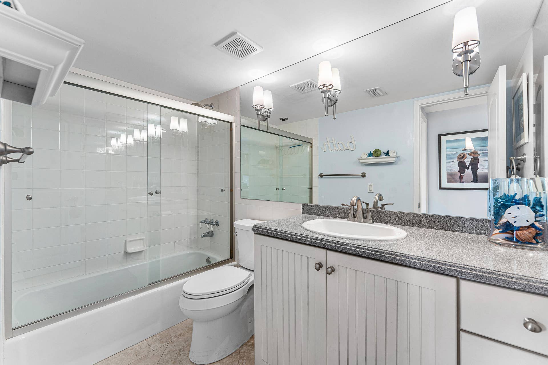 Full-length mirror extending above a vanity with a white oval sink, brushed nickel faucet, and a speckled countertop