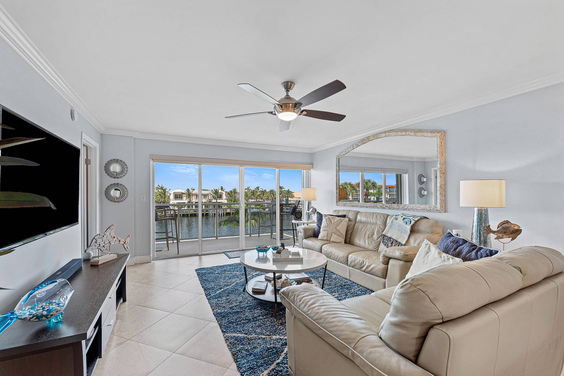 Living area featuring a water view through expansive sliding glass doors, crown molding, and tiled flooring