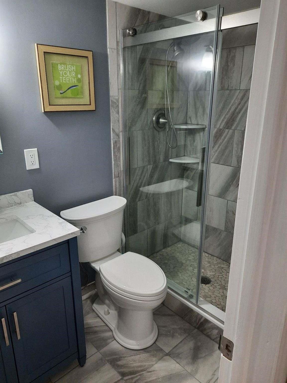 4500 N Federal Highway, #253F, Lighthouse Point, Lighthouse Point, FL 33064 Bathroom featuring a glass-enclosed shower with pebble-style flooring and tile surround