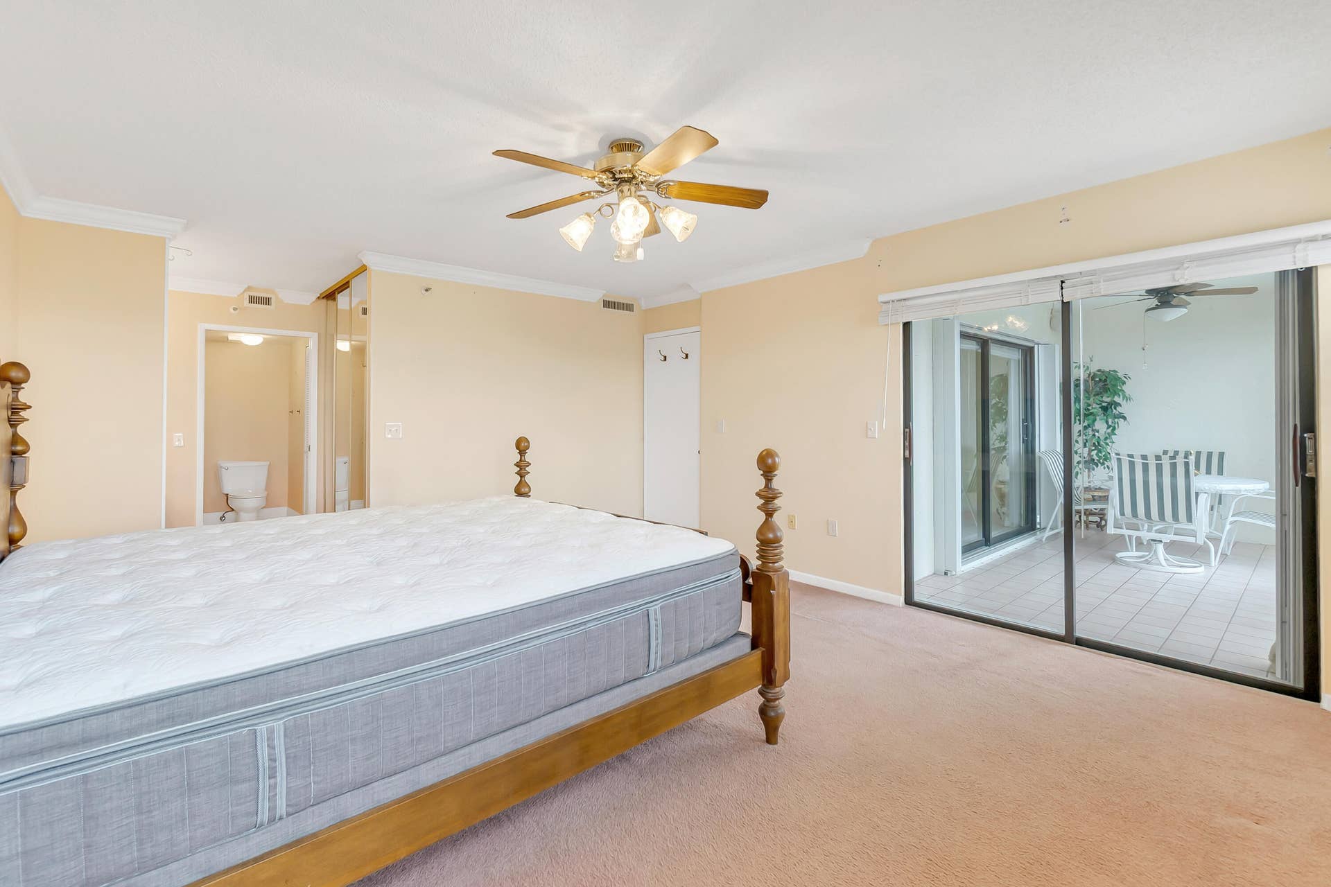 2334 S Cypress Bend Drive, #602, Pompano Beach, FL 33069 Carpeted room featuring a ceiling fan with light fixture, crown molding, and a sliding glass door opening to a tiled outdoor patio