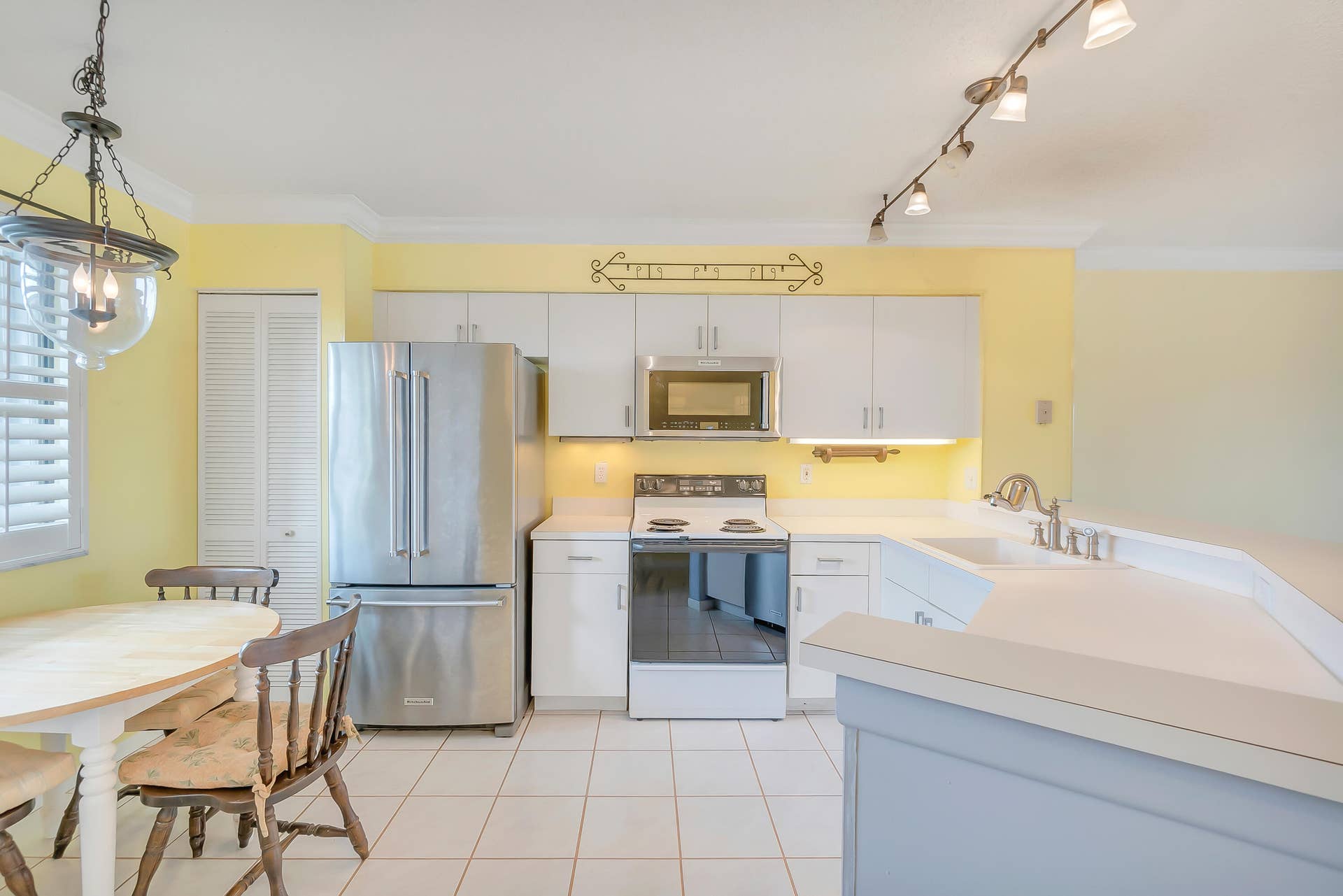 2334 S Cypress Bend Drive, #602, Pompano Beach, FL 33069 Kitchen featuring white cabinetry, light countertops, stainless steel refrigerator, dishwasher and microwave