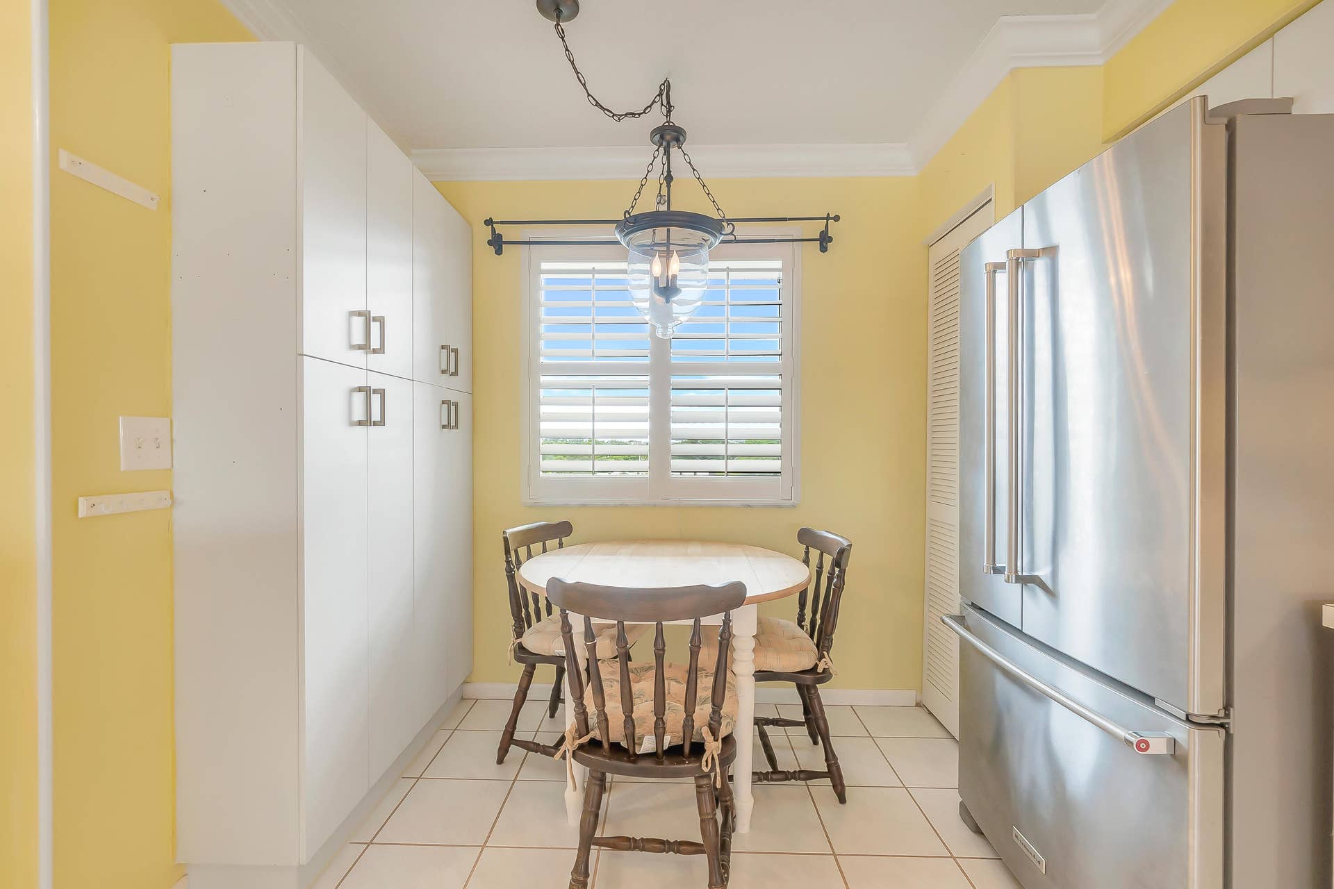 2334 S Cypress Bend Drive, #602, Pompano Beach, FL 33069 Bright kitchen area featuring white cabinetry, a stainless steel French-door refrigerator, and a window with plantation shutters