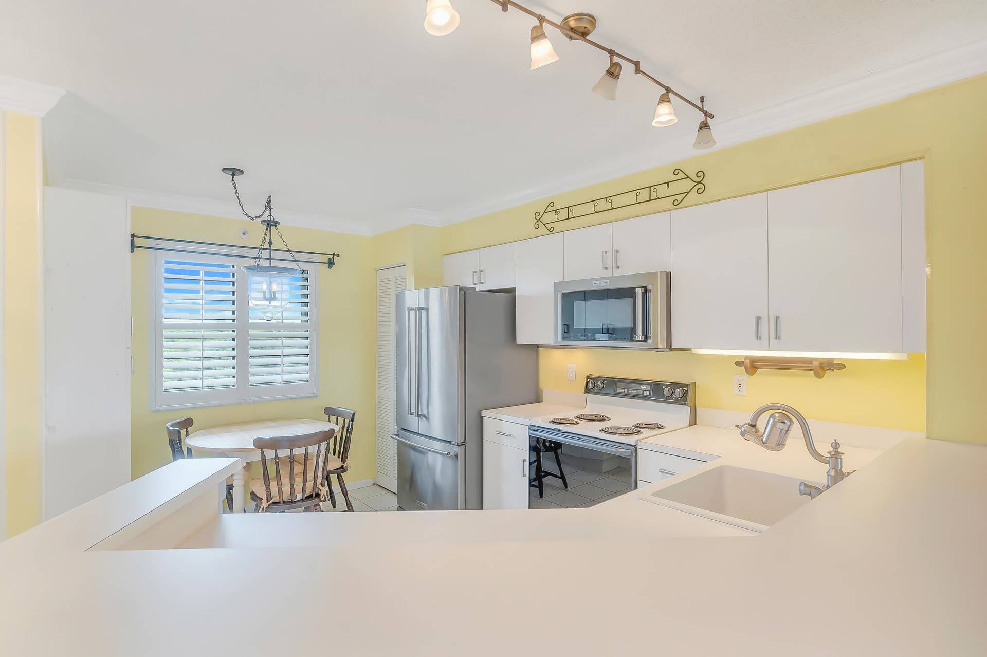 2334 S Cypress Bend Drive, #602, Pompano Beach, FL 33069 Bright kitchen featuring white cabinetry and countertops, newer stainless steel appliances, and track lighting