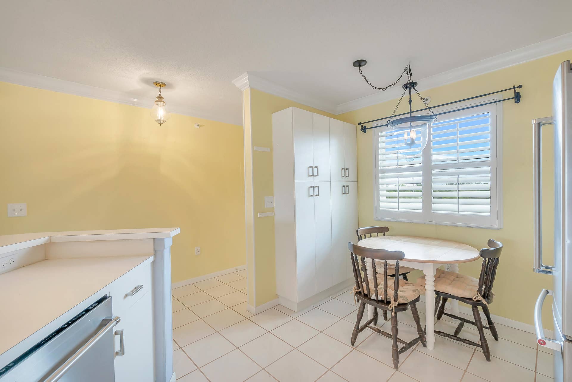 2334 S Cypress Bend Drive, #602, Pompano Beach, FL 33069 Kitchen space featuring tile flooring, white cabinetry, plantation shutters, and crown molding