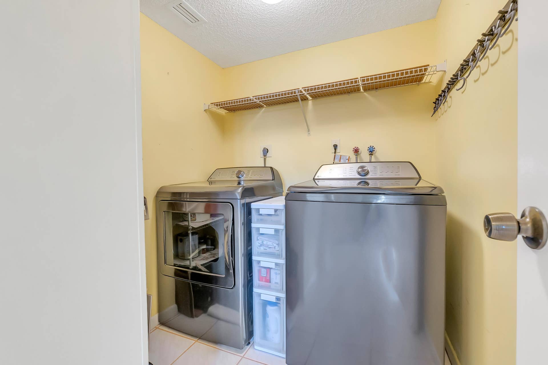2334 S Cypress Bend Drive, #602, Pompano Beach, FL 33069 Dedicated utility space featuring newer over-sized washer/dryer, tile flooring and lots of shelving