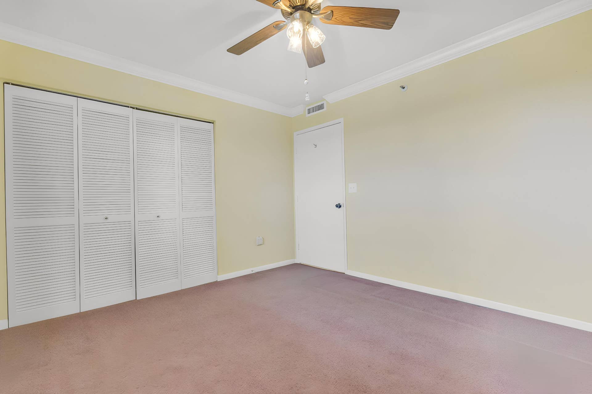 2334 S Cypress Bend Drive, #602, Pompano Beach, FL 33069 Guest/2nd bedroom featuring louvered bi-fold closet doors containing closet systemic, crown molding, a ceiling fan with light fixture, and a solid white door