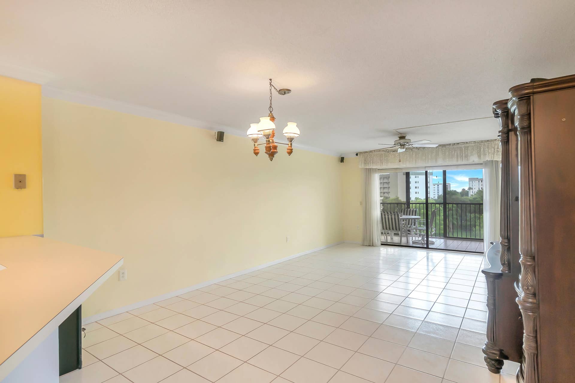 2334 S Cypress Bend Drive, #602, Pompano Beach, FL 33069 Spacious living/dining area featuring white tile flooring, a multi-light chandelier, a ceiling fan, and crown molding