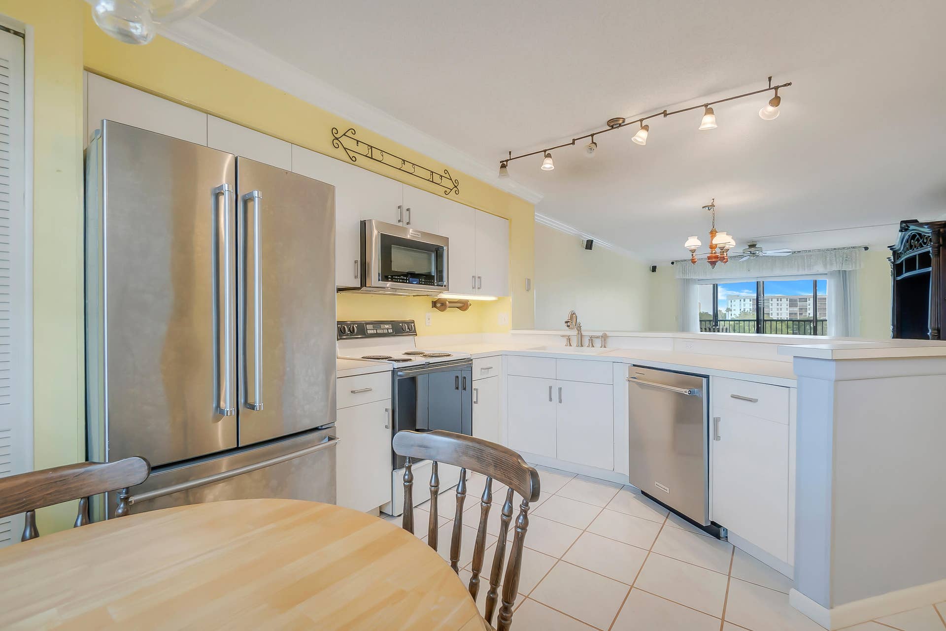 2334 S Cypress Bend Drive, #602, Pompano Beach, FL 33069 Kitchen featuring white cabinetry, stainless steel appliances, tile flooring, and track lighting