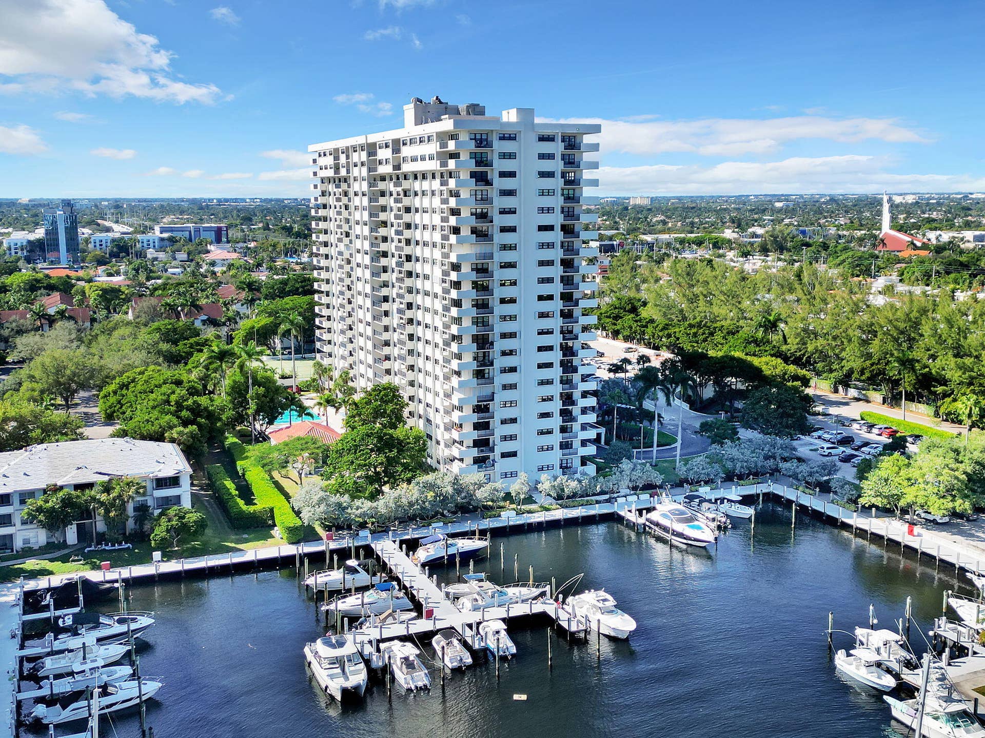 3200 Port Royale Drive N, #902, Fort Lauderdale, FL 33308 High-rise residential building featuring multiple private balconies, an onsite marina with numerous boat slips, a terraced swimming pool, and extensive landscaping