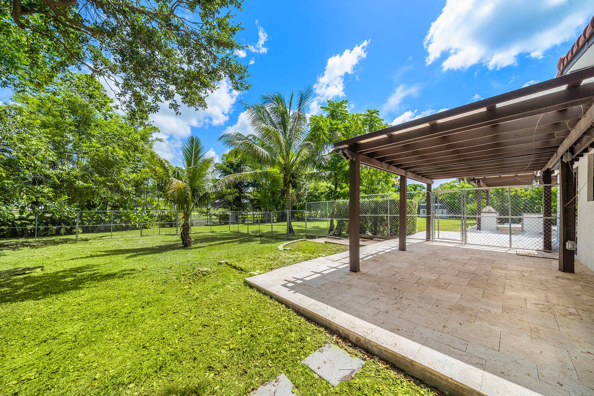 4950 Thoroughbred Lane, Southwest Ranches, FL 33330 Expansive sideyard featuring a pergola-covered patio with stone pavers, mature trees, and a spacious lawn