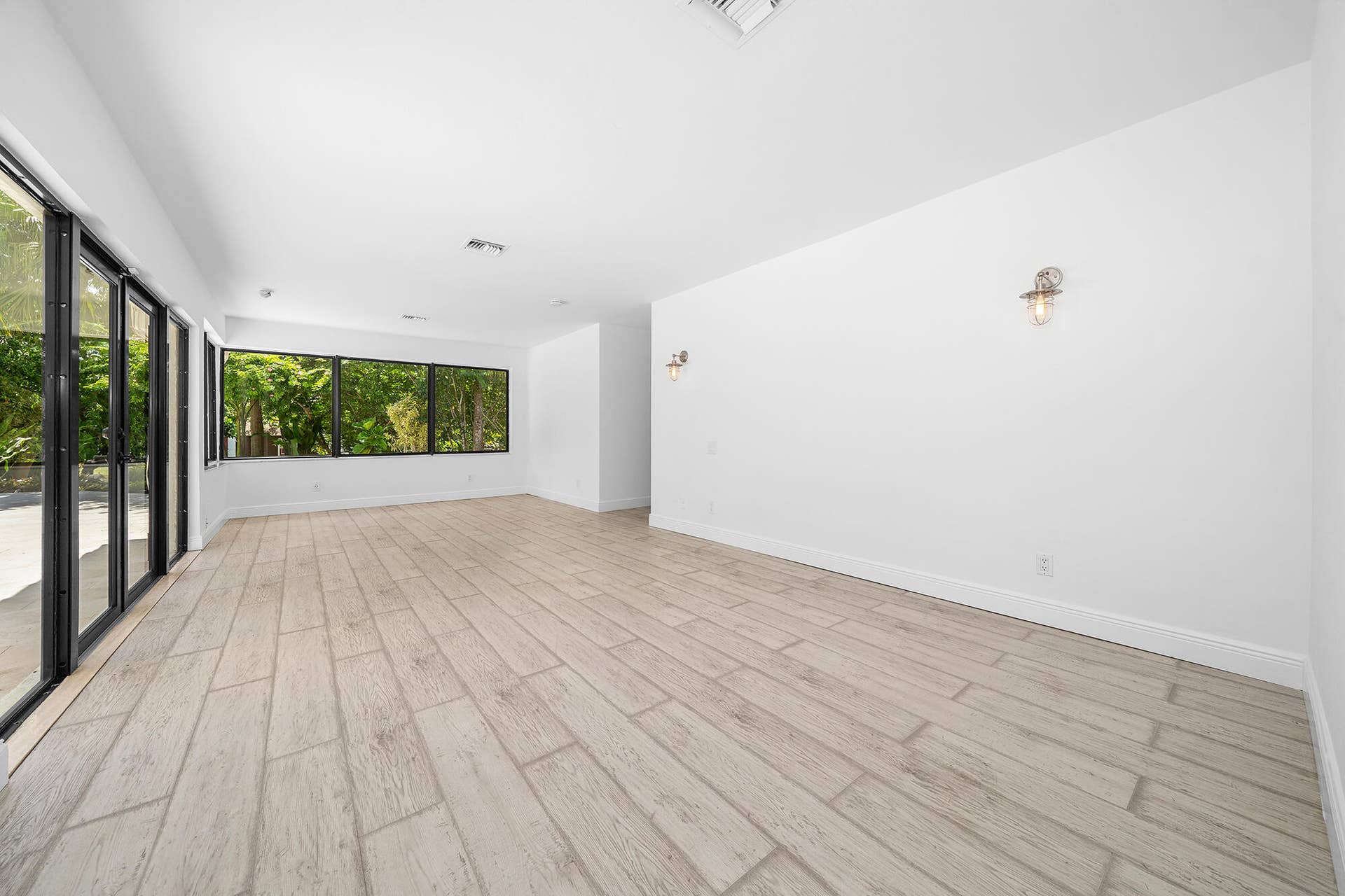4950 Thoroughbred Lane, Southwest Ranches, FL 33330 Bright interior space featuring wood-finish flooring, white walls, and contemporary wall sconces