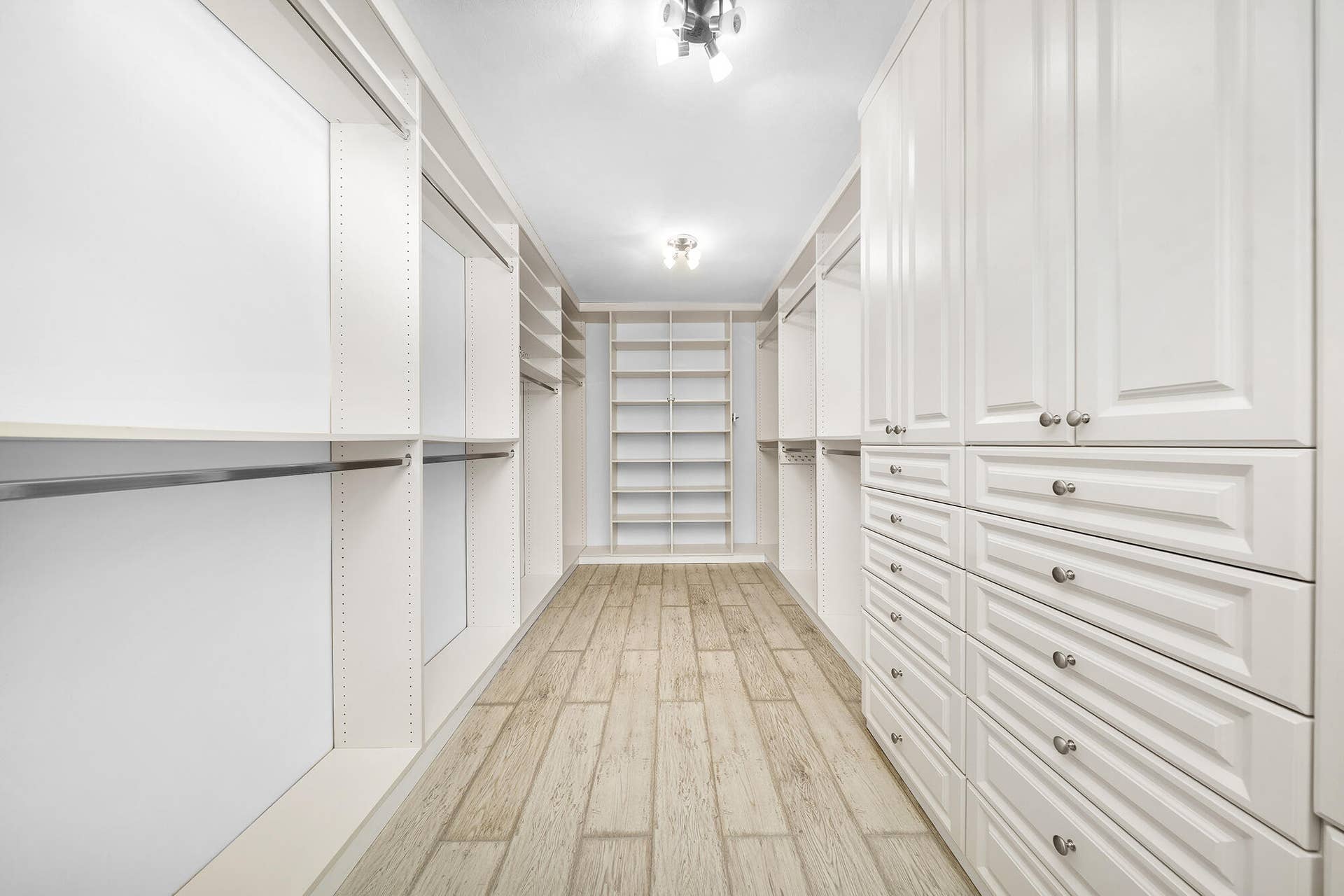 4950 Thoroughbred Lane, Southwest Ranches, FL 33330 Walk-in closet featuring extensive built-in cabinetry, shelving, hanging rods, and wood-finish flooring