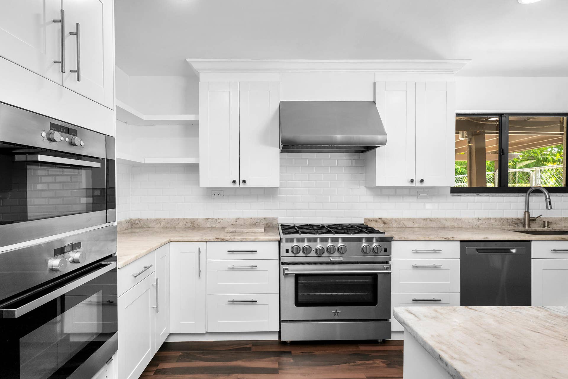 4950 Thoroughbred Lane, Southwest Ranches, FL 33330 Modern kitchen featuring white shaker cabinetry, stainless steel appliances, light-toned countertops, subway tile backsplash, and dark wood-finish flooring