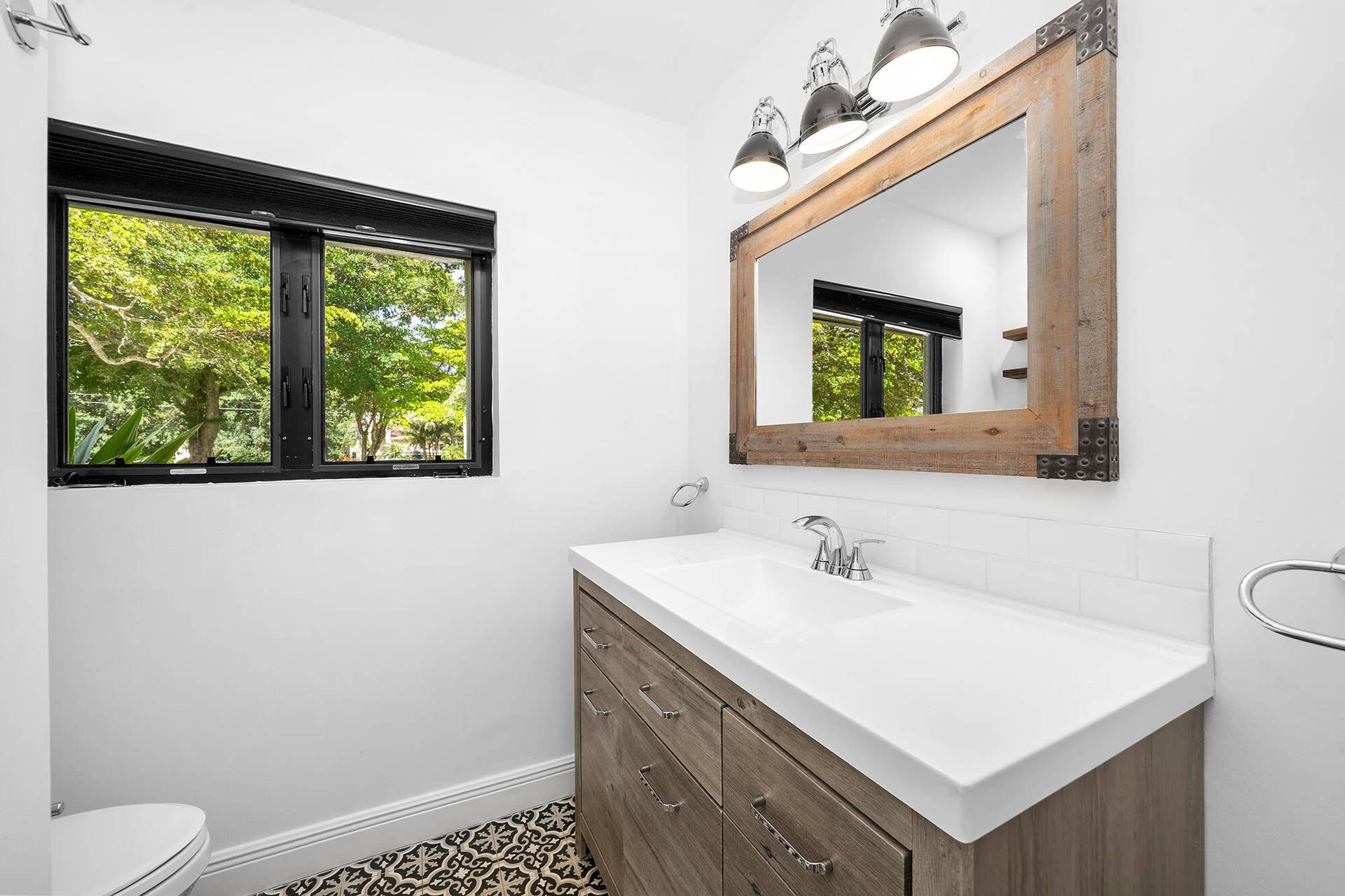 4950 Thoroughbred Lane, Southwest Ranches, FL 33330 Bathroom featuring a wood-finish vanity with an integrated white sink and countertop, subway tile backsplash, and a large wood-framed mirror