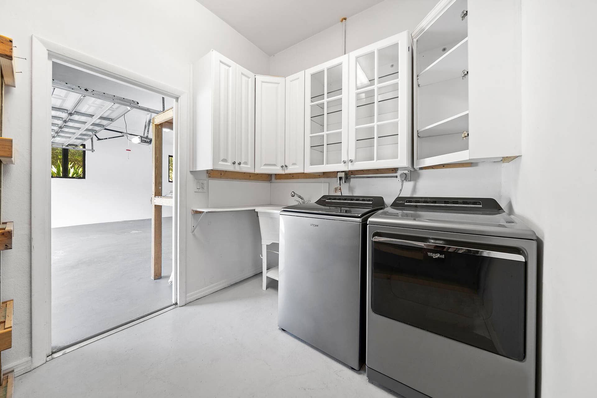 4950 Thoroughbred Lane, Southwest Ranches, FL 33330 Dedicated utility space featuring white upper cabinetry, glass-front cabinets, a built-in sink, and a washer and dryer