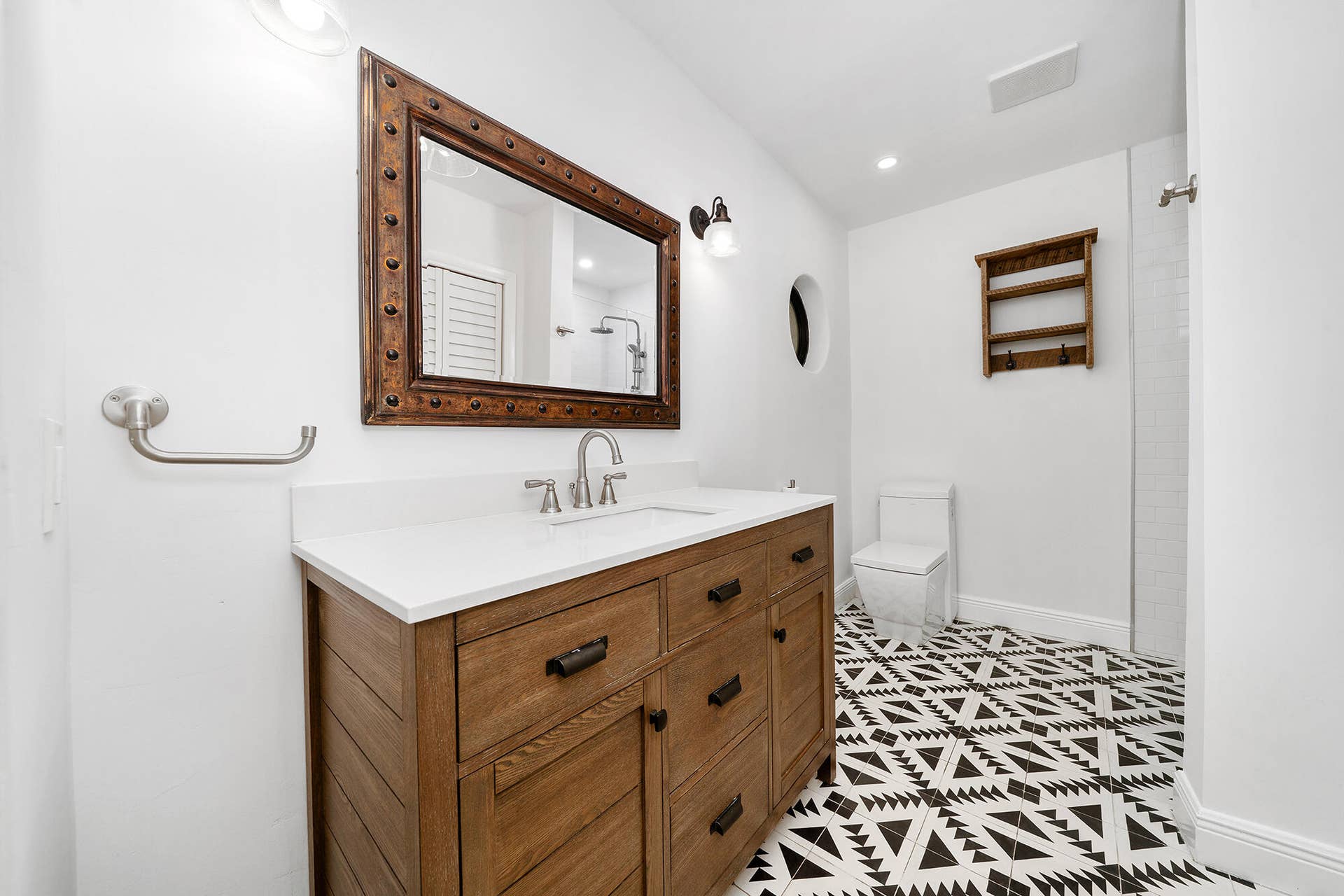 4950 Thoroughbred Lane, Southwest Ranches, FL 33330 Bathroom featuring a wood-finish vanity with a white countertop, patterned floor tile, and a framed mirror