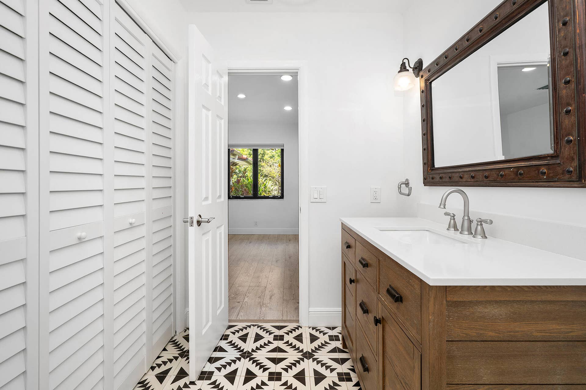 4950 Thoroughbred Lane, Southwest Ranches, FL 33330 Bathroom featuring patterned floor tiles, a wood-finish vanity with a white countertop and integrated sink, a large framed mirror, and a glass-enclosed shower with white subway tile