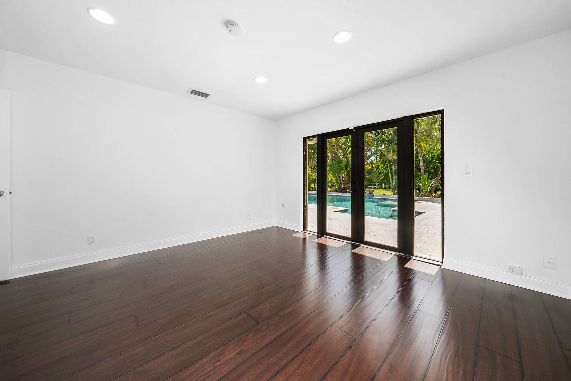4950 Thoroughbred Lane, Southwest Ranches, FL 33330 Spacious interior room with wood-finish flooring, recessed lighting, and glass doors leading to patio, pool, and outside oasis.