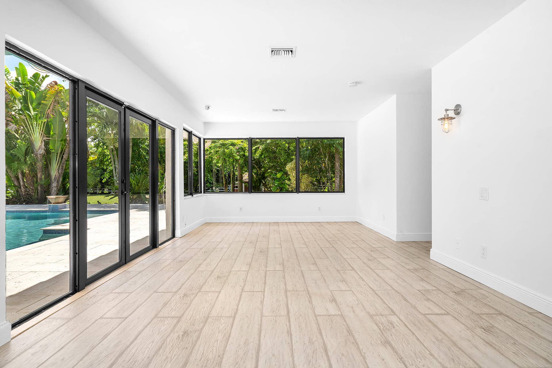 4950 Thoroughbred Lane, Southwest Ranches, FL 33330 Spacious room with wood-finish flooring, white walls, and contemporary black-framed glass doors