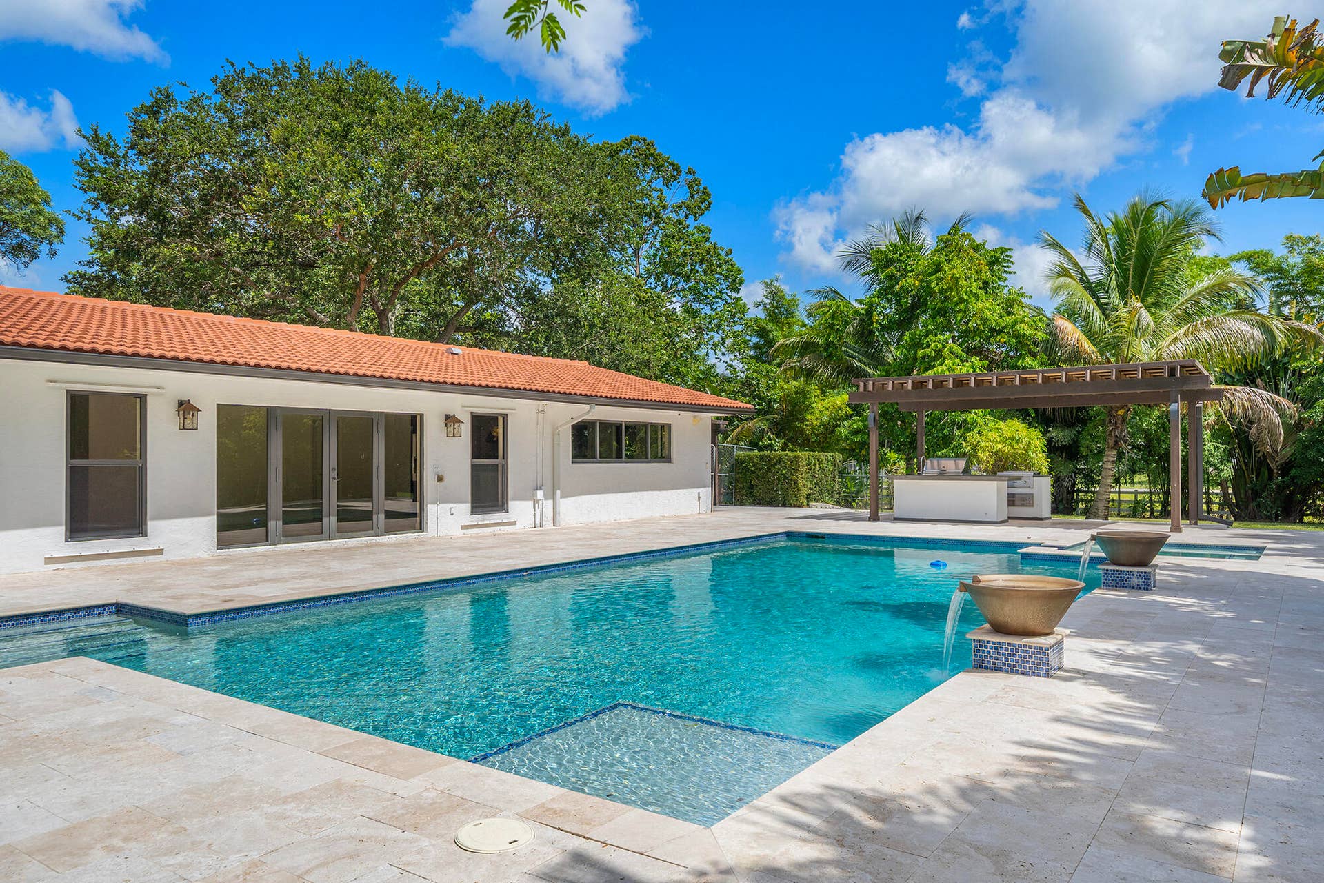 4950 Thoroughbred Lane, Southwest Ranches, FL 33330 Expansive outdoor living area featuring a rectangular swimming pool with integrated spa, a paved patio, and a pergola-covered outdoor kitchen
