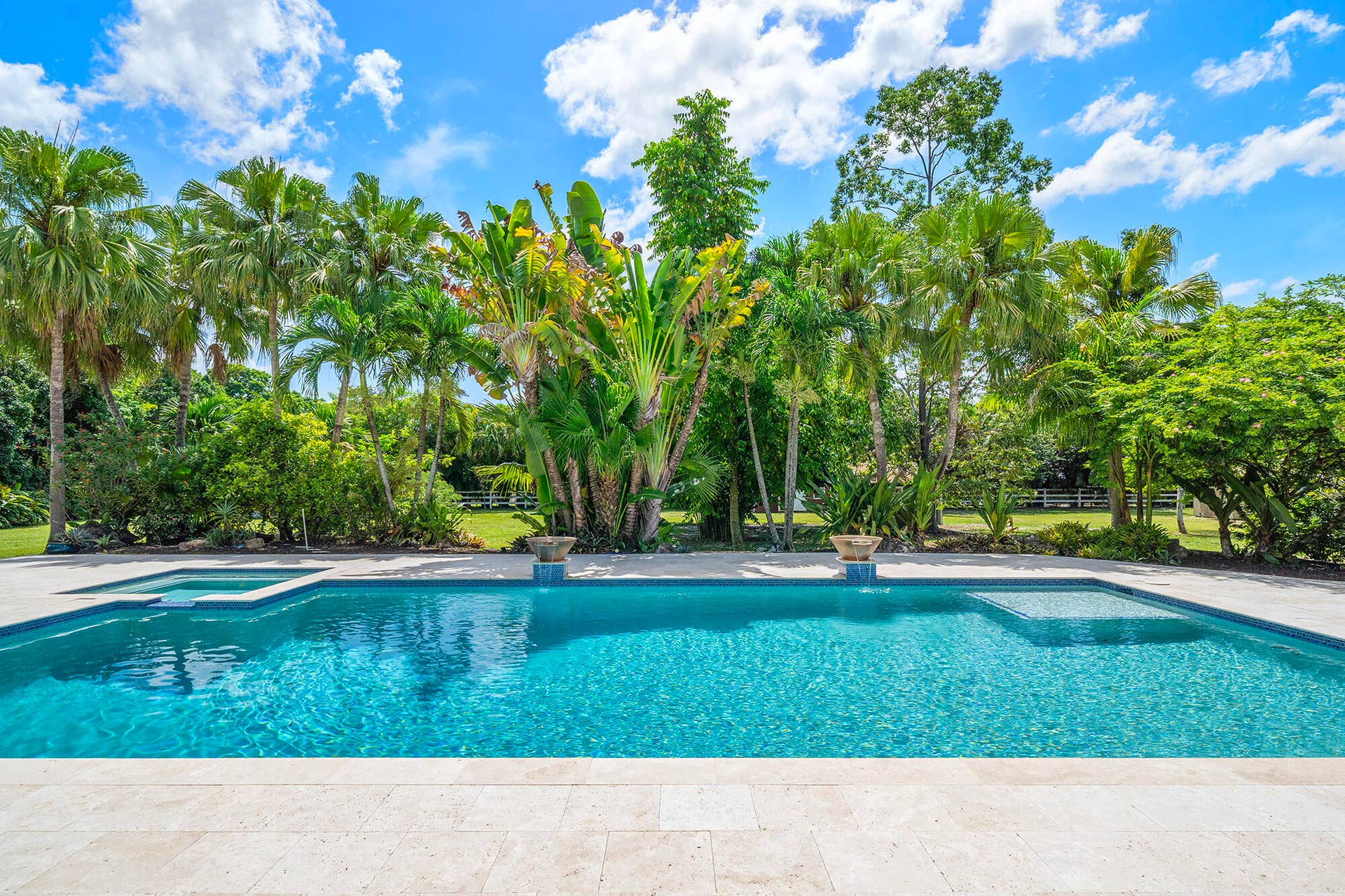 4950 Thoroughbred Lane, Southwest Ranches, FL 33330 Resort-style pool with integrated spa and surrounding paver deck, framed by lush tropical landscaping and mature palm trees