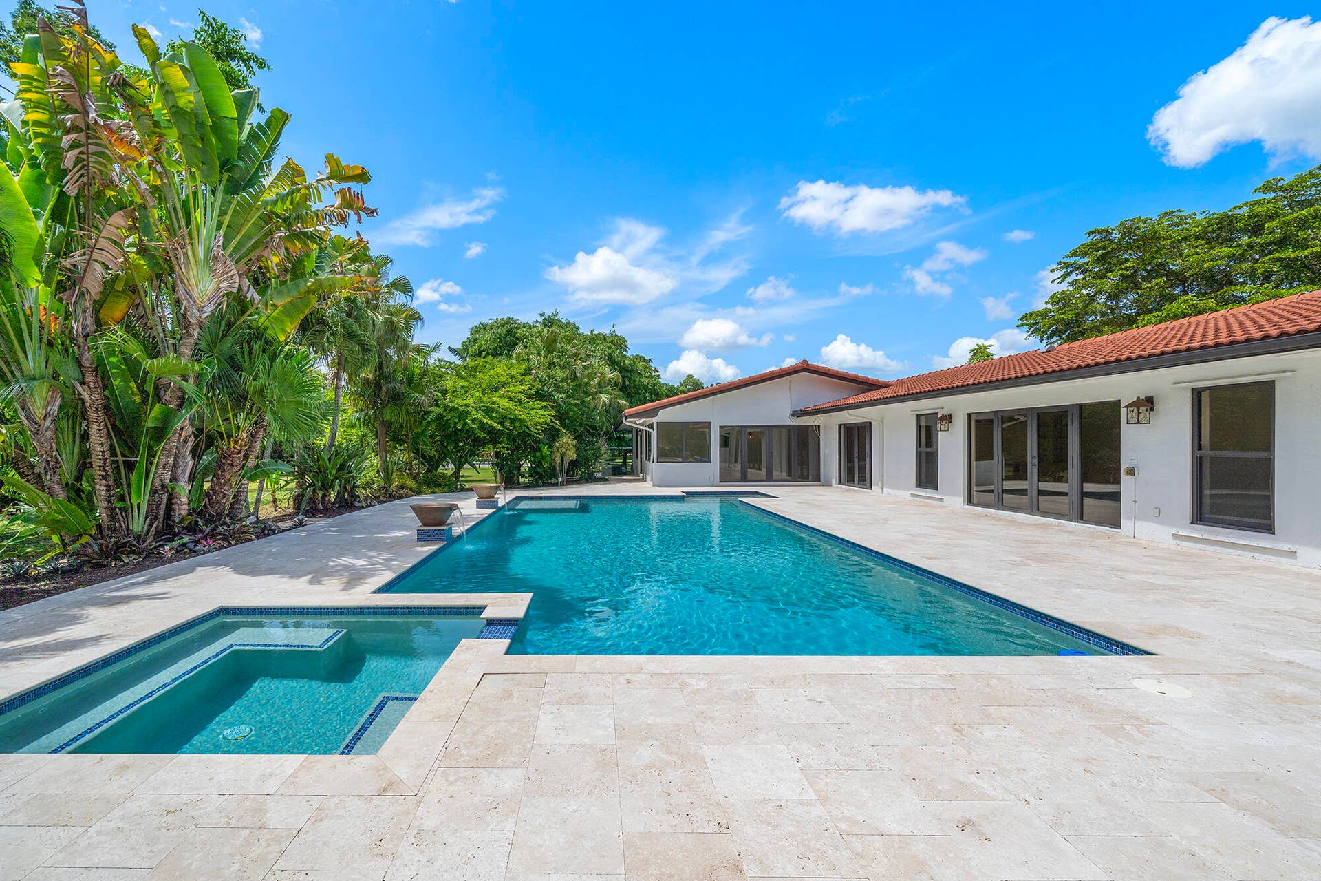 4950 Thoroughbred Lane, Southwest Ranches, FL 33330 Expansive outdoor living area featuring a rectangular swimming pool, integrated spa, and light-toned travertine marble paver decking