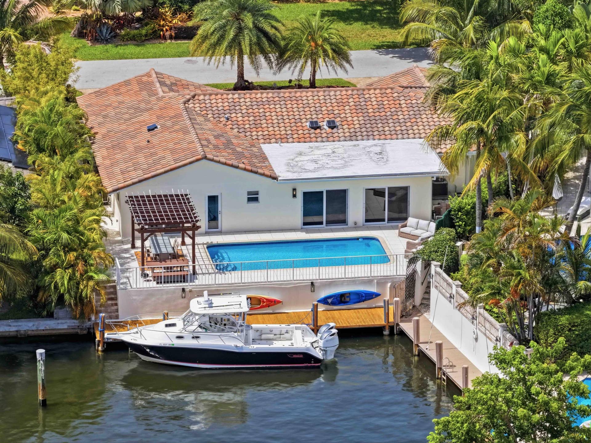 3316 NE 40TH Court, Fort Lauderdale, FL 33308 Waterfront residence with a private boat dock, featuring a pool deck, a pergola-covered patio, and a tile roof
