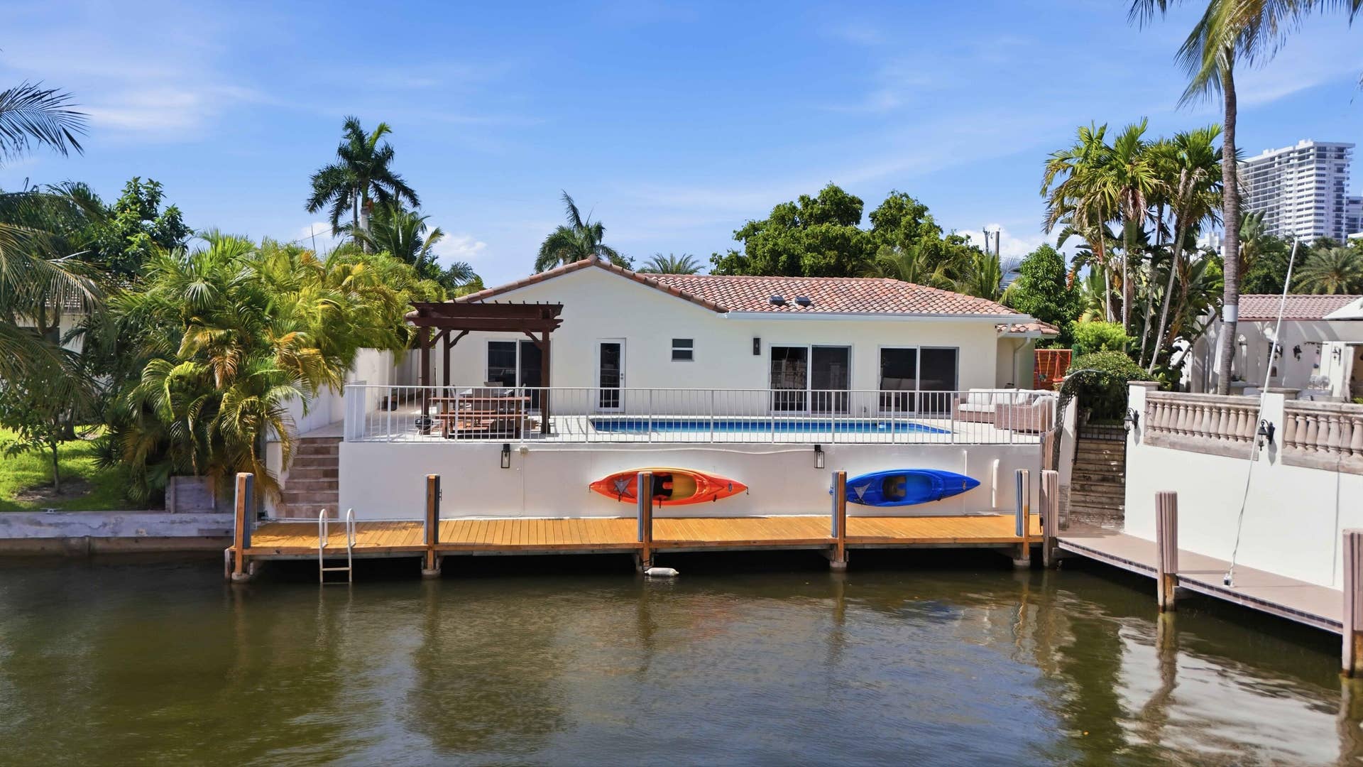 3316 NE 40TH Court, Fort Lauderdale, FL 33308 Waterfront property featuring a private dock with direct water access, a pool deck with a pergola, and a tiled roof residence