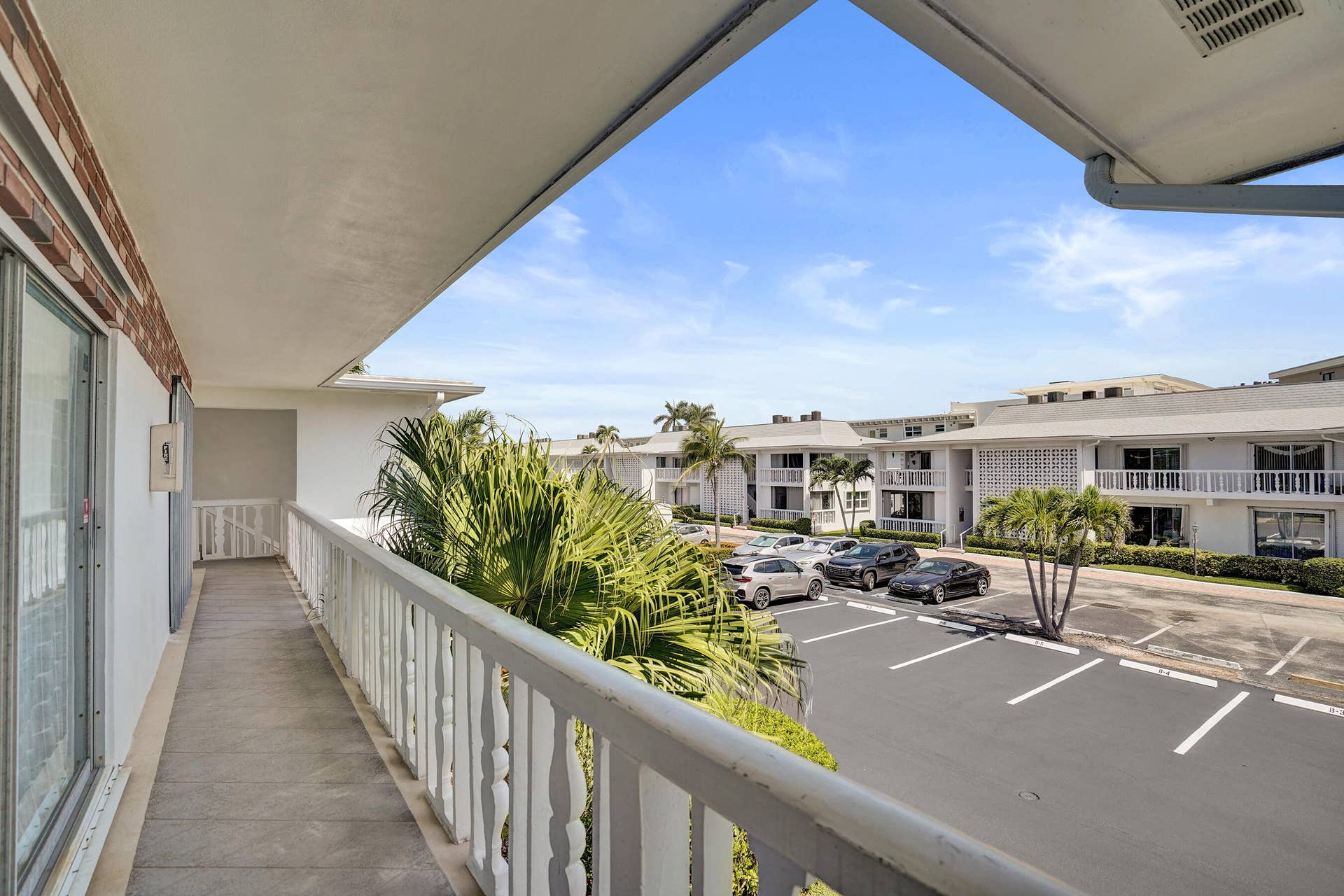 Expansive covered balcony featuring a concrete floor and white spindle railing