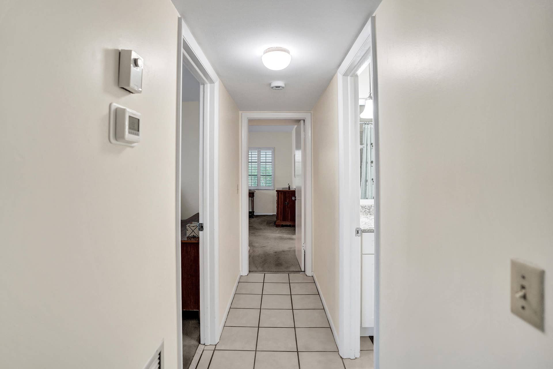 Neutral painted hallway with square tile flooring