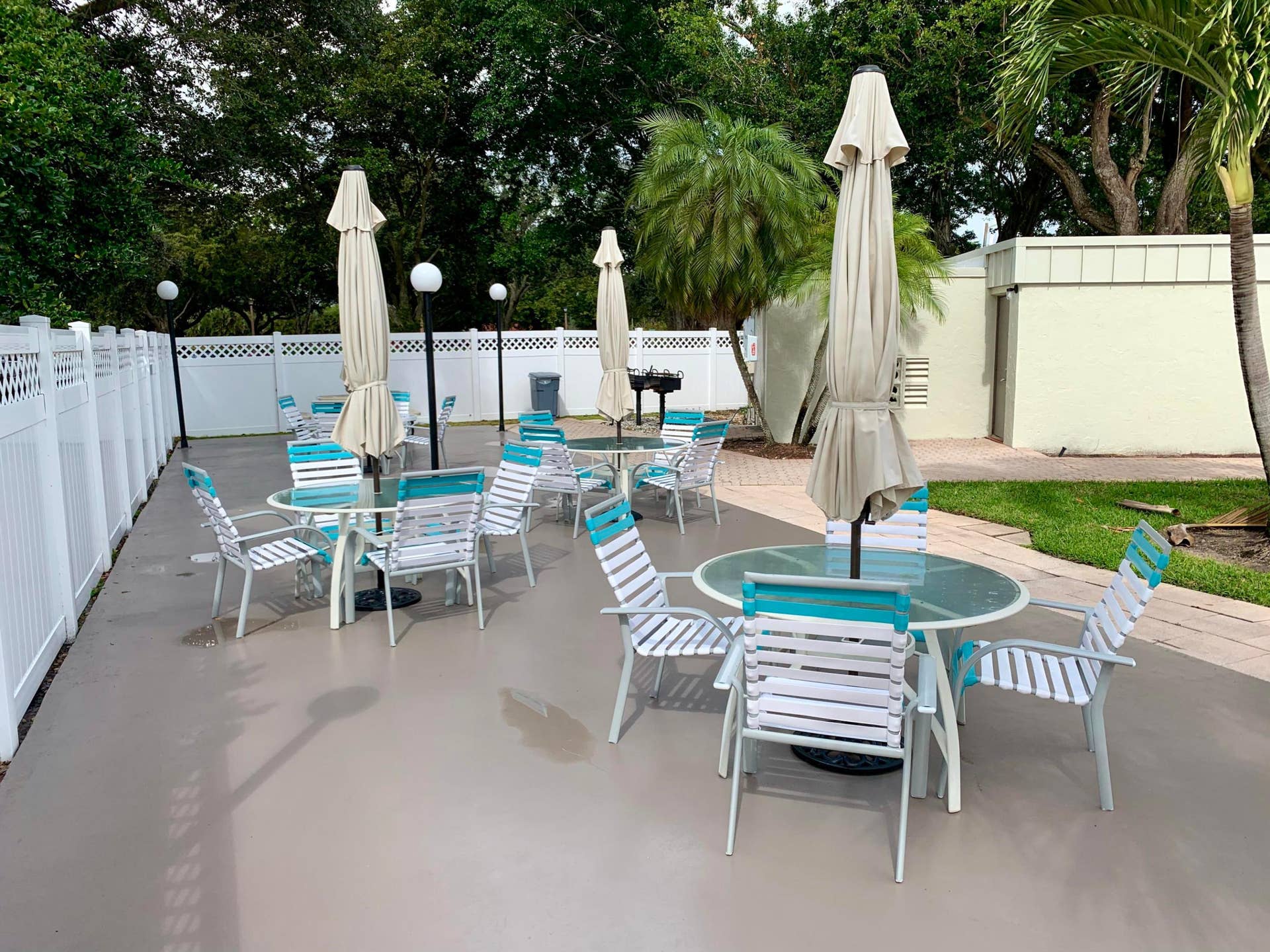 3100 W Rolling Hills Circle, #309, Davie, Davie, FL 33328 Spacious outdoor patio area featuring multiple seating arrangements, a built-in barbecue grill, perimeter fencing, and mature landscaping