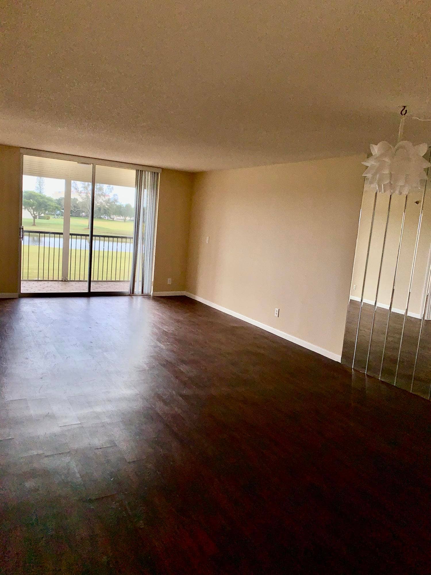 3100 W Rolling Hills Circle, #309, Davie, Davie, FL 33328 Spacious interior featuring dark wood-finish flooring, neutral wall tones, and a sliding glass door leading to a private balcony