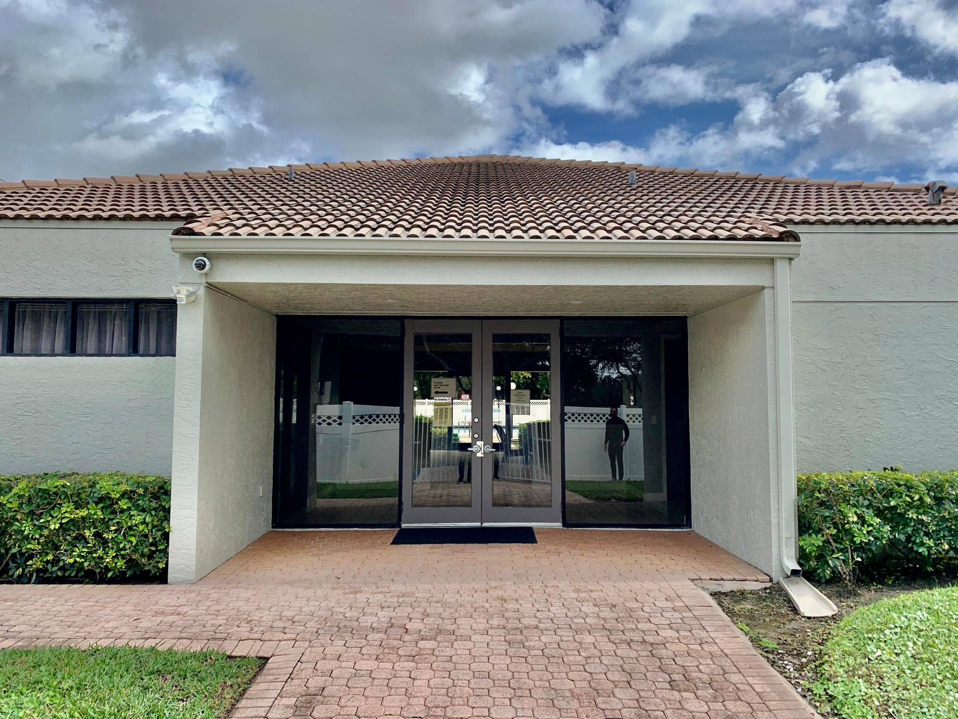 3100 W Rolling Hills Circle, #309, Davie, Davie, FL 33328 Entryway featuring a terra cotta tile roof, large glass double doors, a brick paver pathway, and surrounding landscaping