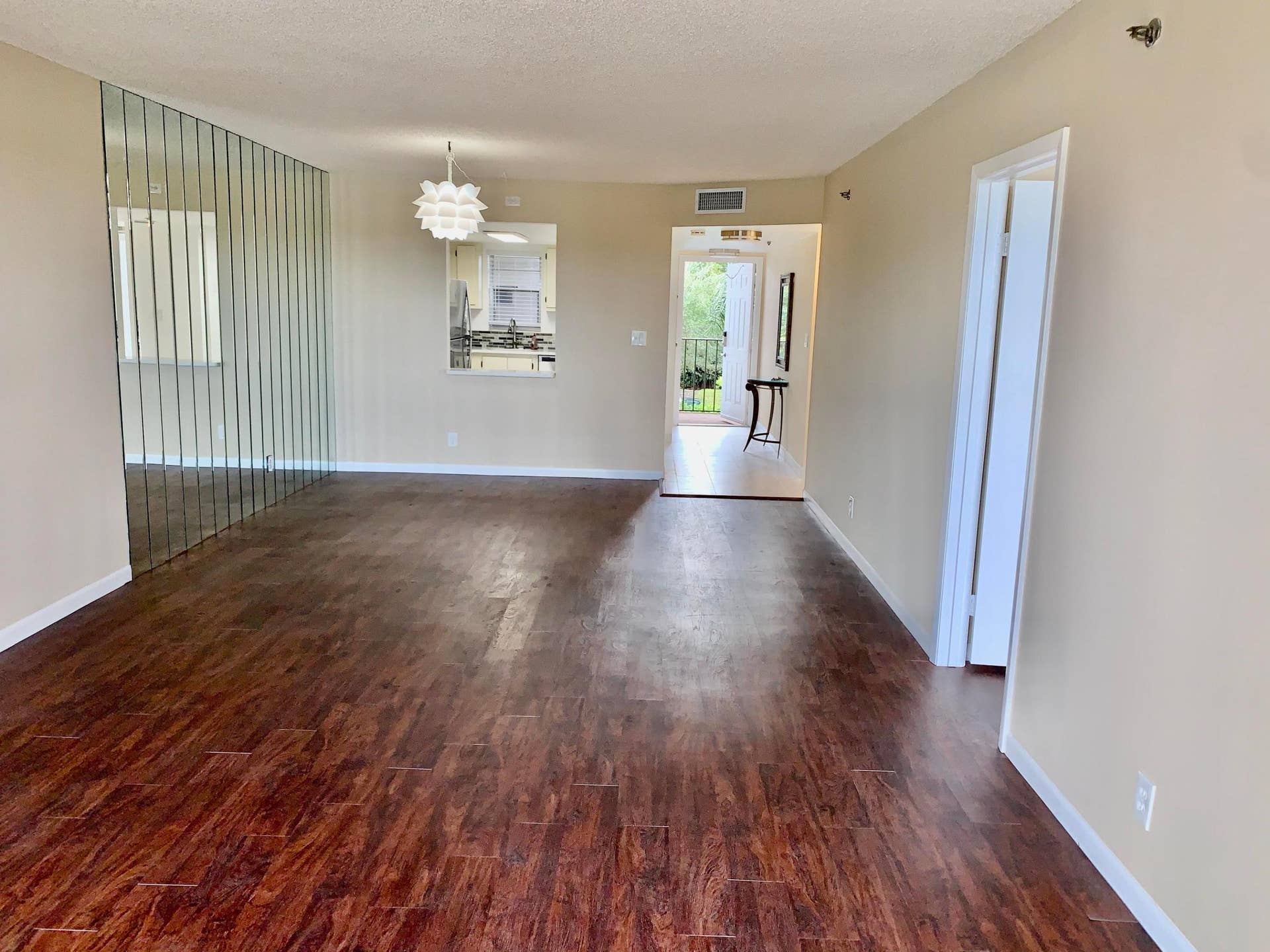 3100 W Rolling Hills Circle, #309, Davie, Davie, FL 33328 Spacious interior featuring wood-finish flooring, neutral-toned walls, and a decorative mirror wall accent