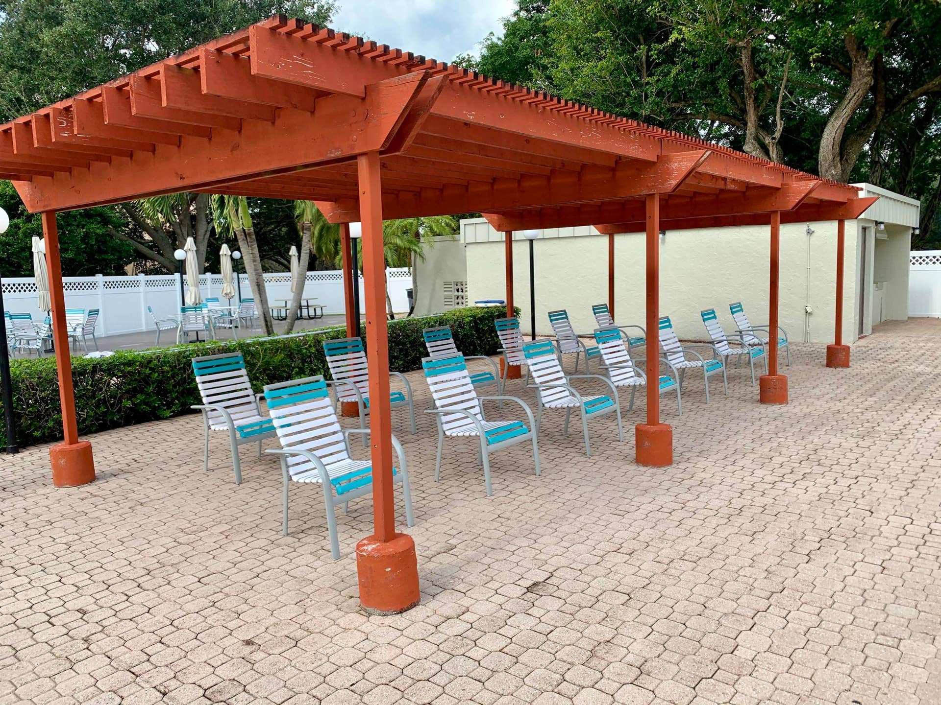 3100 W Rolling Hills Circle, #309, Davie, Davie, FL 33328 Expansive paver patio featuring a large wooden pergola structure, low privacy hedge, and a white lattice fence boundary