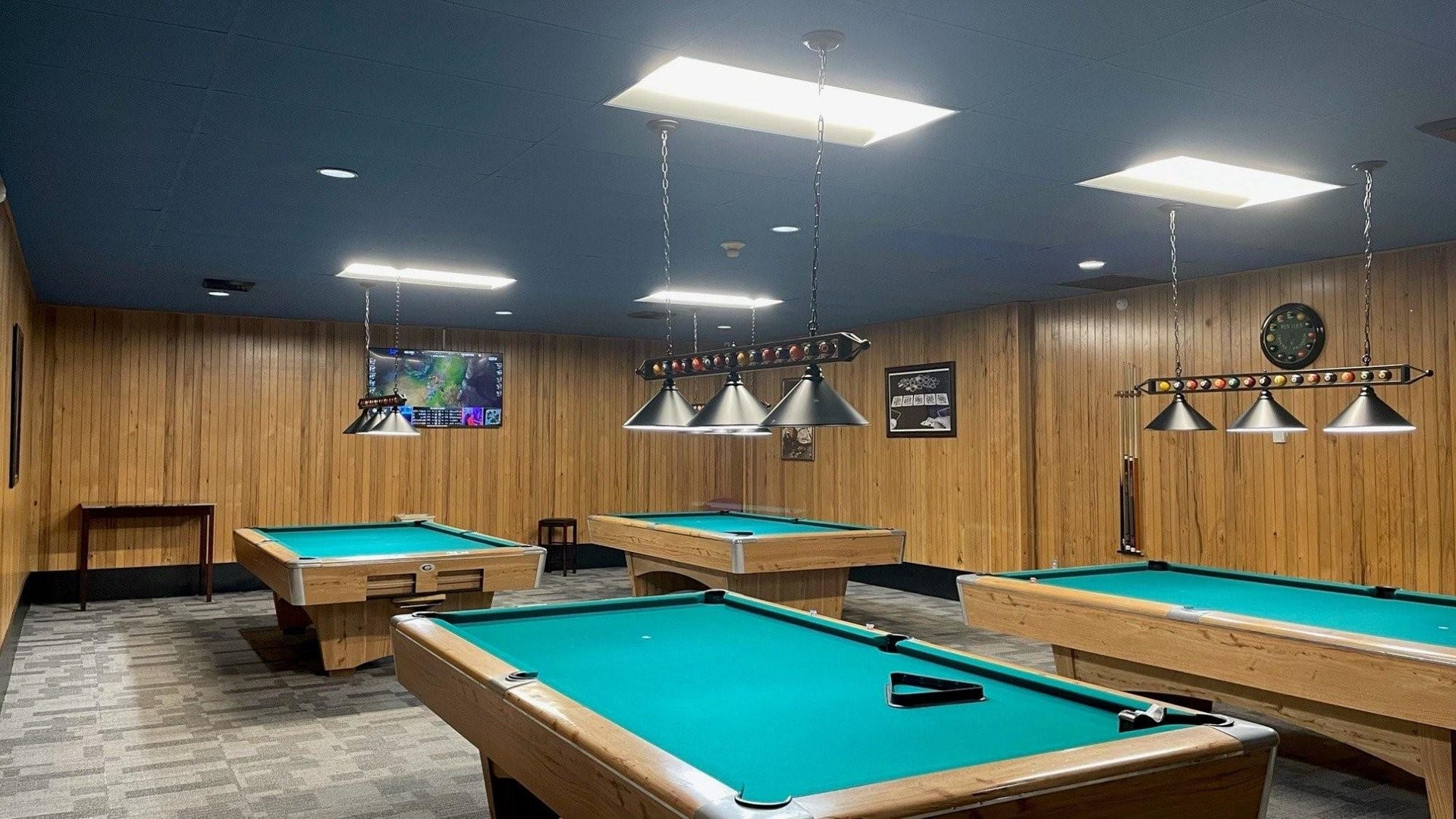Recreation room featuring multiple billiard tables, wood-paneled walls, and recessed lighting