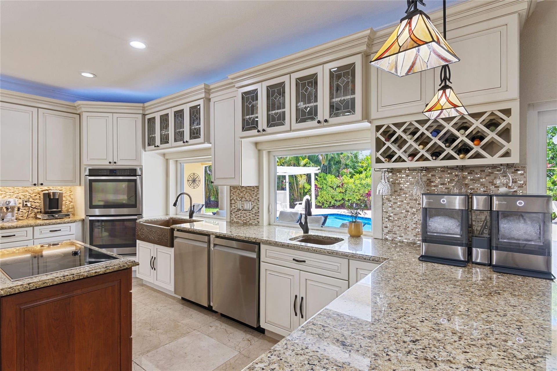 Gourmet kitchen featuring granite countertops, cream cabinetry, stainless steel appliances, and a mosaic tile backsplash
