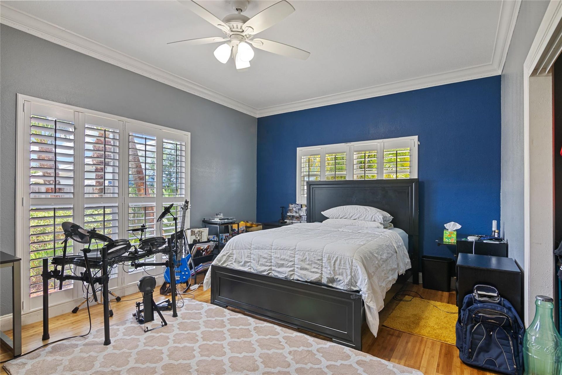 Hardwood flooring extends throughout this space featuring crown molding and a ceiling fan