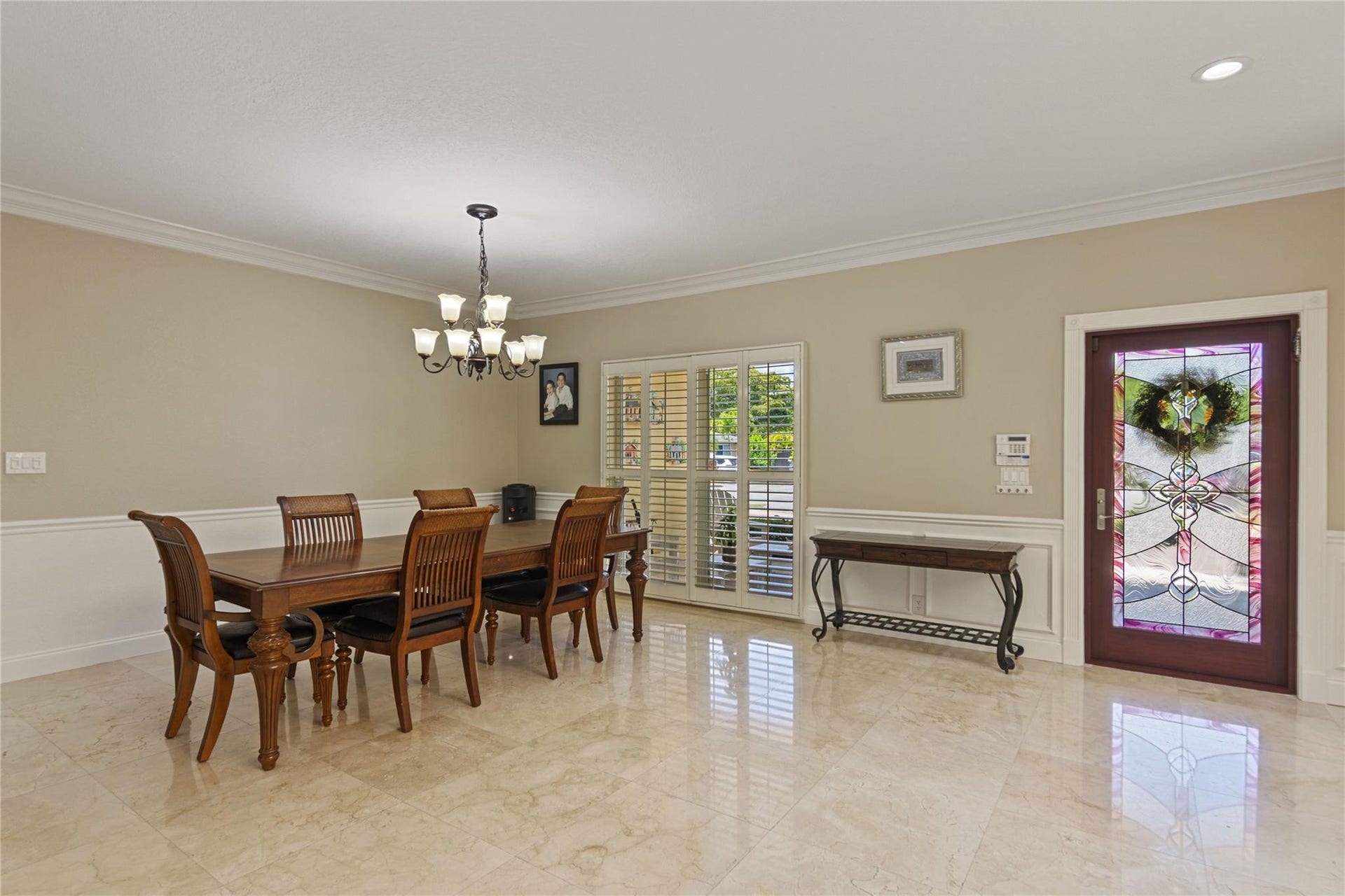 Spacious entry area featuring light-toned tile flooring, crown molding, and wainscoting