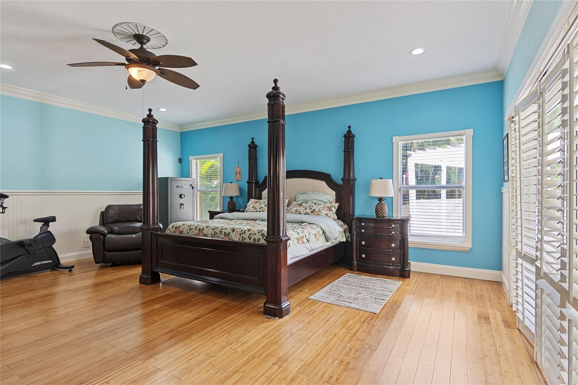 Spacious room featuring wood-finish flooring, light blue walls, and white wainscoting