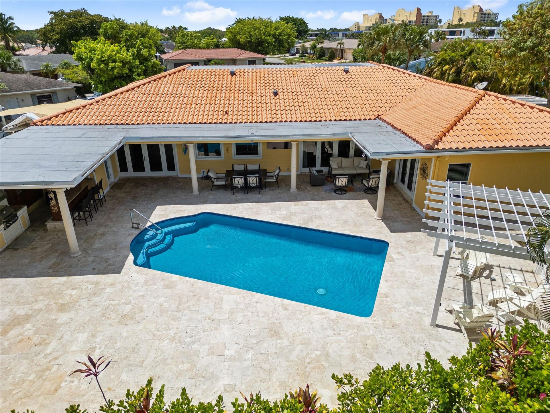 Outdoor living space featuring a blue-tiled swimming pool and extensive stone-tiled patio