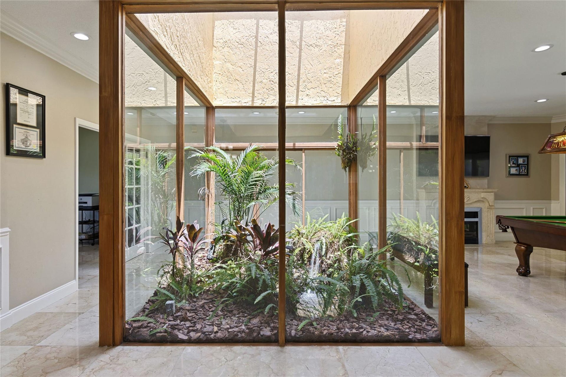 Atrium with glass enclosure featuring various plantings, natural wood-finish framing, and a skylight