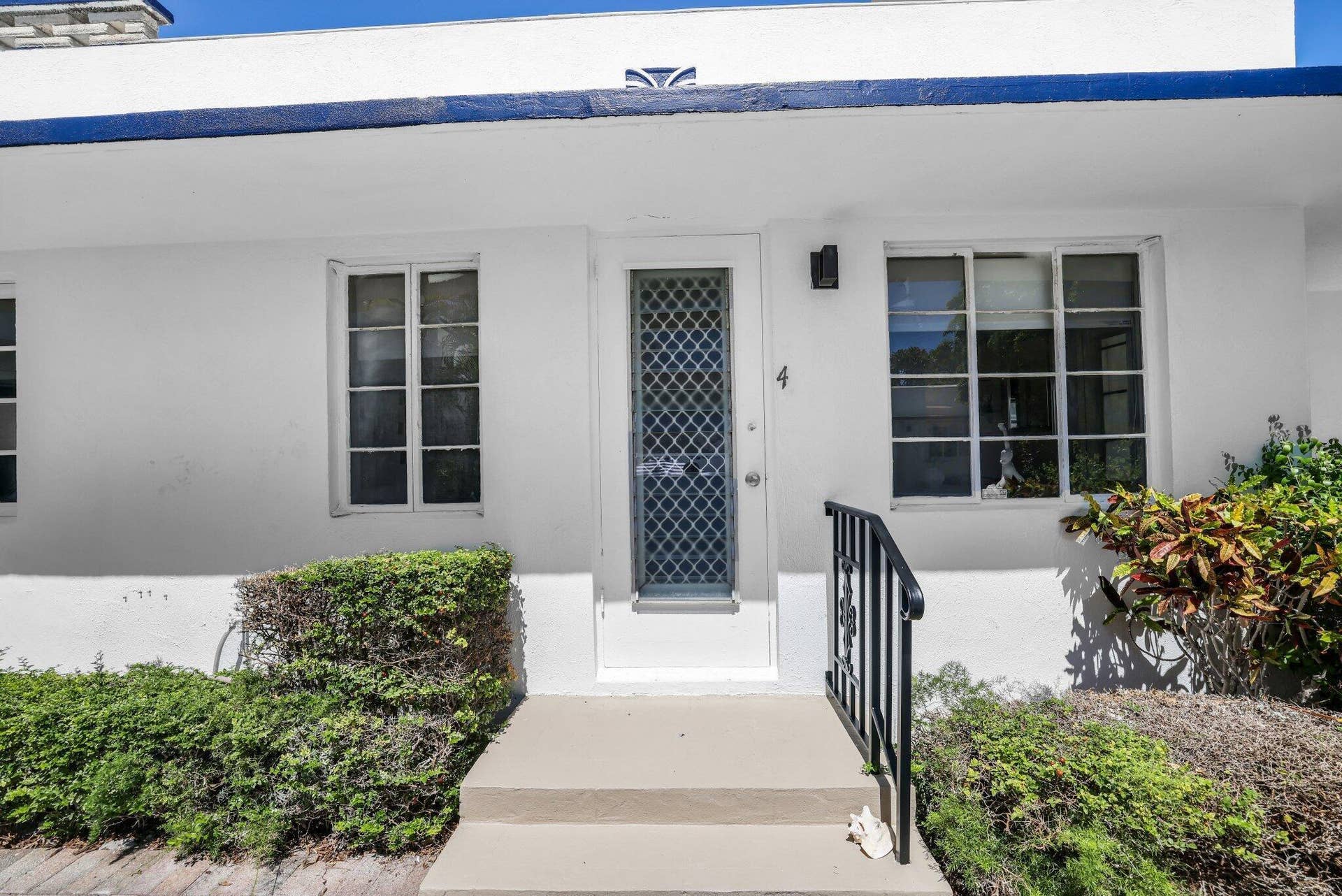 320 Inlet Way, #4, Palm Beach Shores, Palm Beach Shores, FL 33404 White stucco exterior with a blue trim accent, featuring multiple pane windows and a screen door with a decorative grid