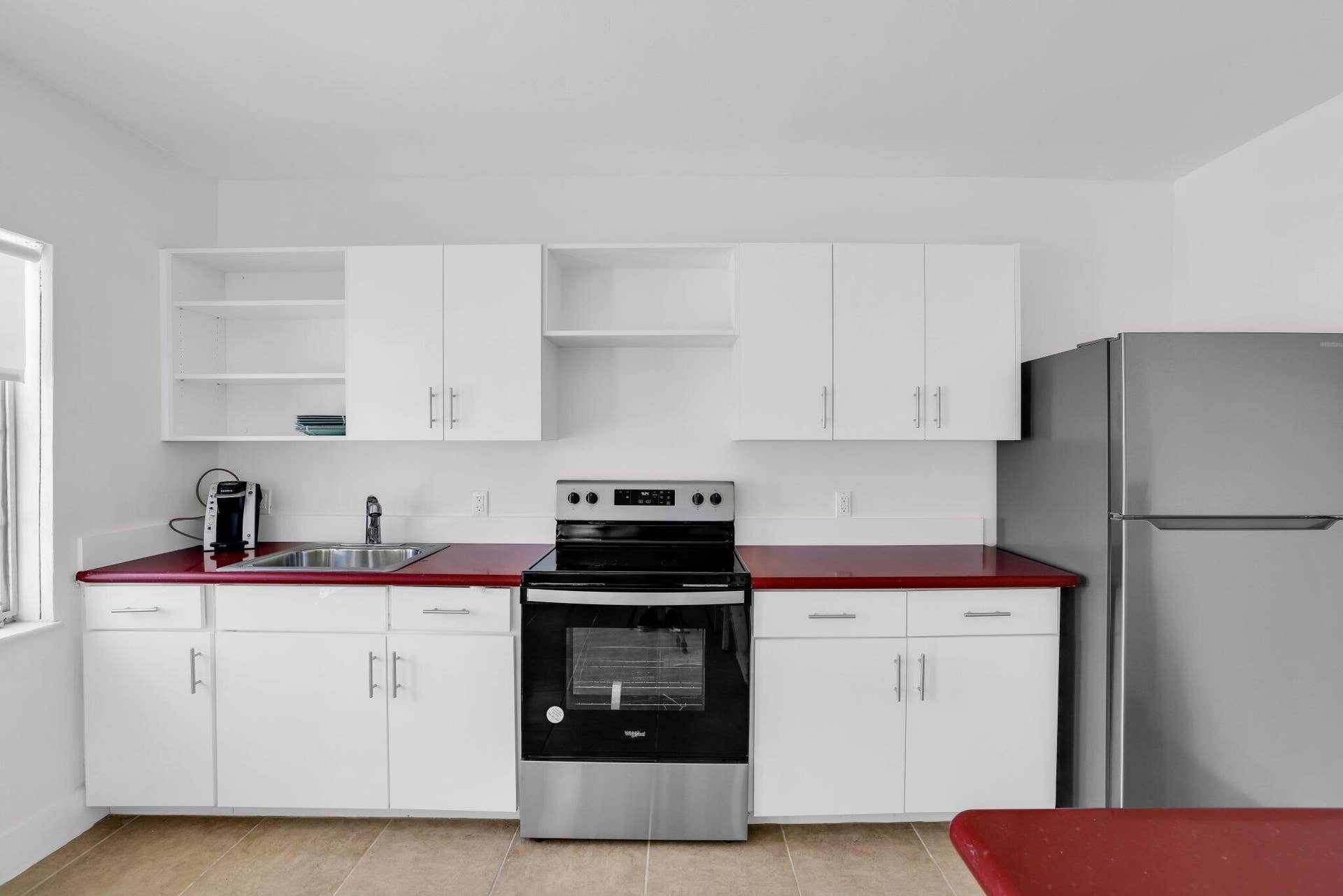 320 Inlet Way, #4, Palm Beach Shores, Palm Beach Shores, FL 33404 Modern kitchen featuring white cabinetry, stainless steel appliances, a stainless steel sink, and bold red countertops