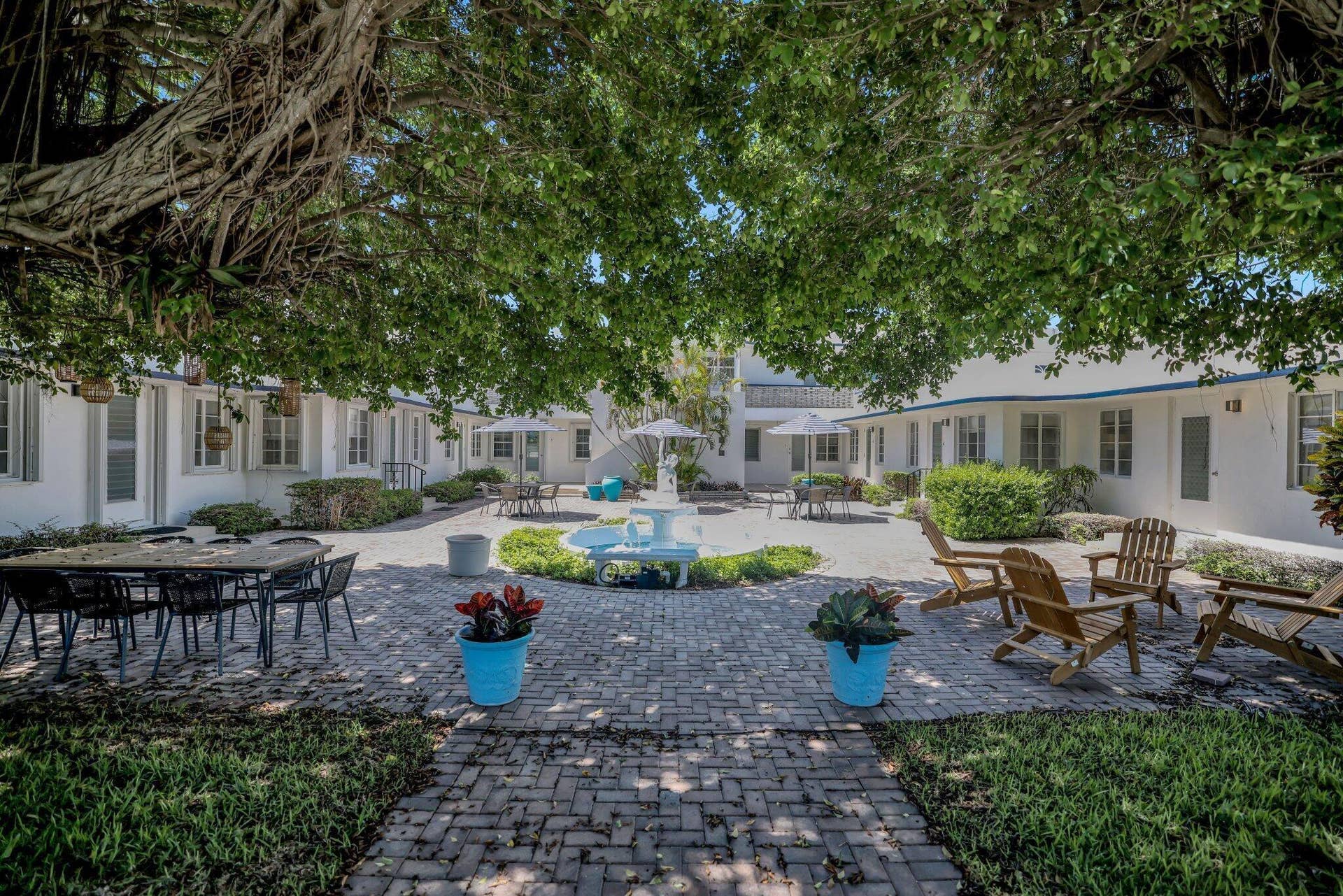 320 Inlet Way, #4, Palm Beach Shores, Palm Beach Shores, FL 33404 Spacious paver patio courtyard featuring a central fountain, mature trees, and white stucco buildings