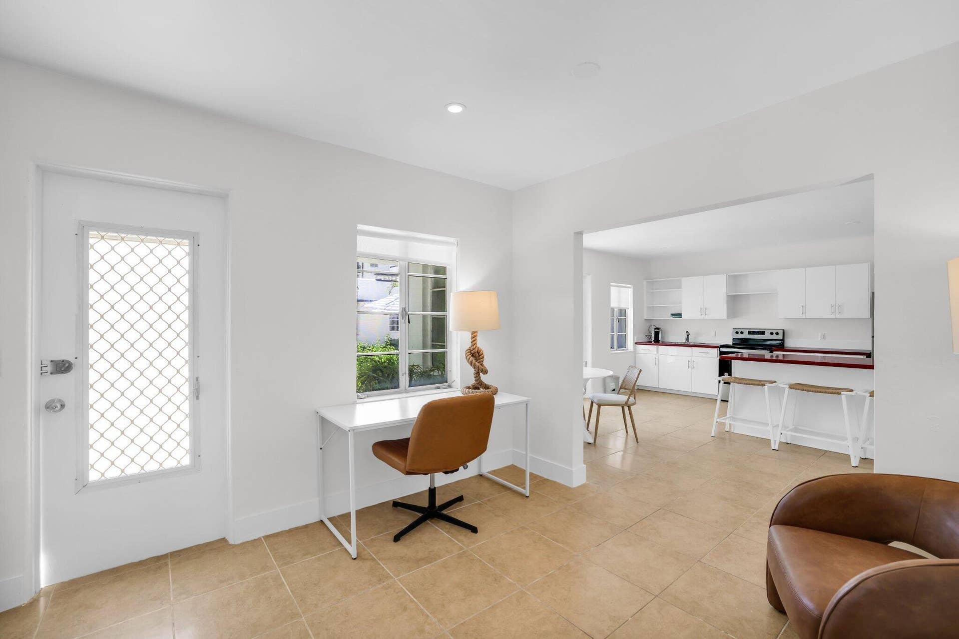 320 Inlet Way, #4, Palm Beach Shores, Palm Beach Shores, FL 33404 Bright interior with tile flooring, a white safety screen door, and a kitchen featuring white cabinetry and red countertops