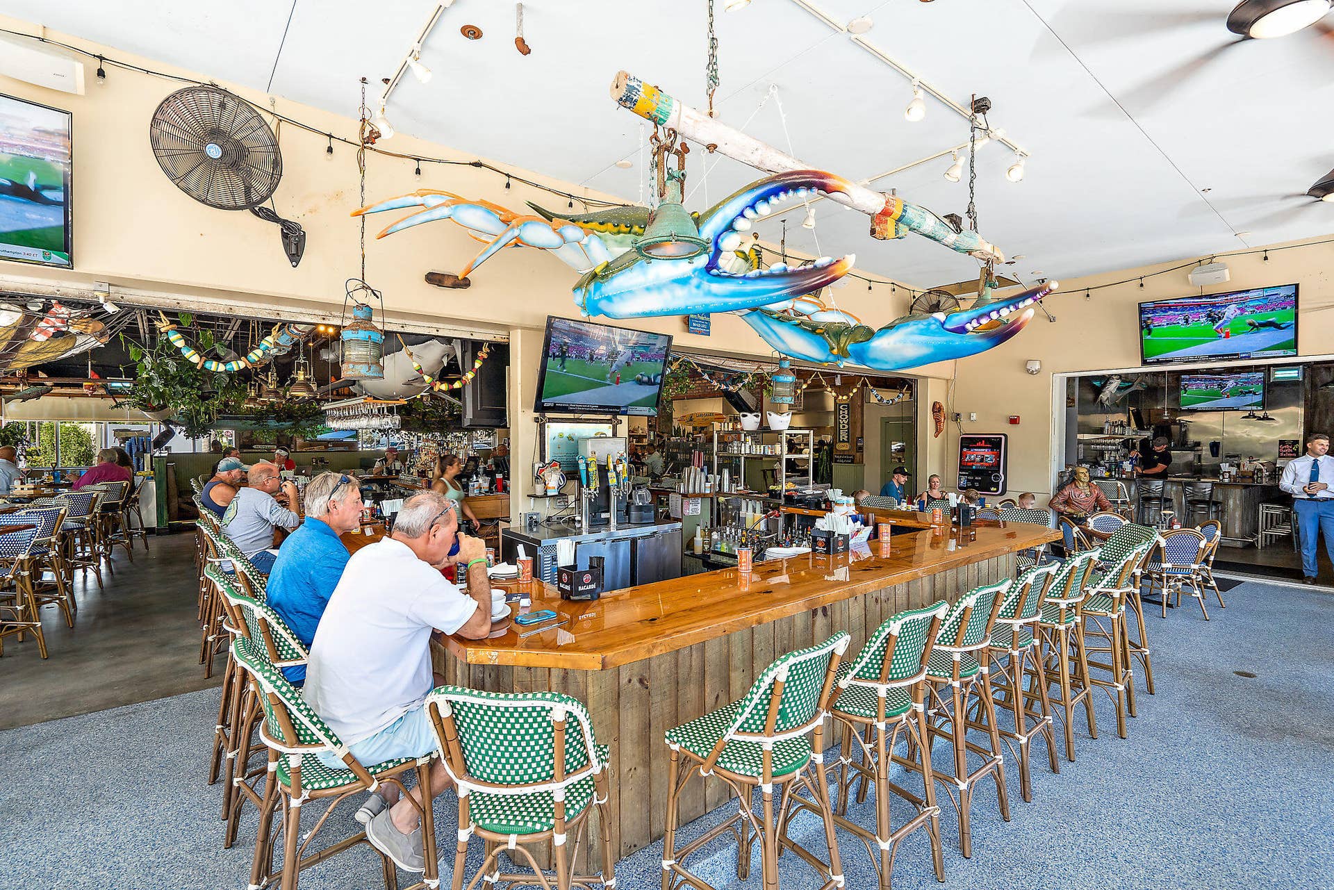 320 Inlet Way, #4, Palm Beach Shores, Palm Beach Shores, FL 33404 Spacious bar area featuring a polished wood-top bar, woven bar stools, multiple ceiling fans, and overhead decorative elements