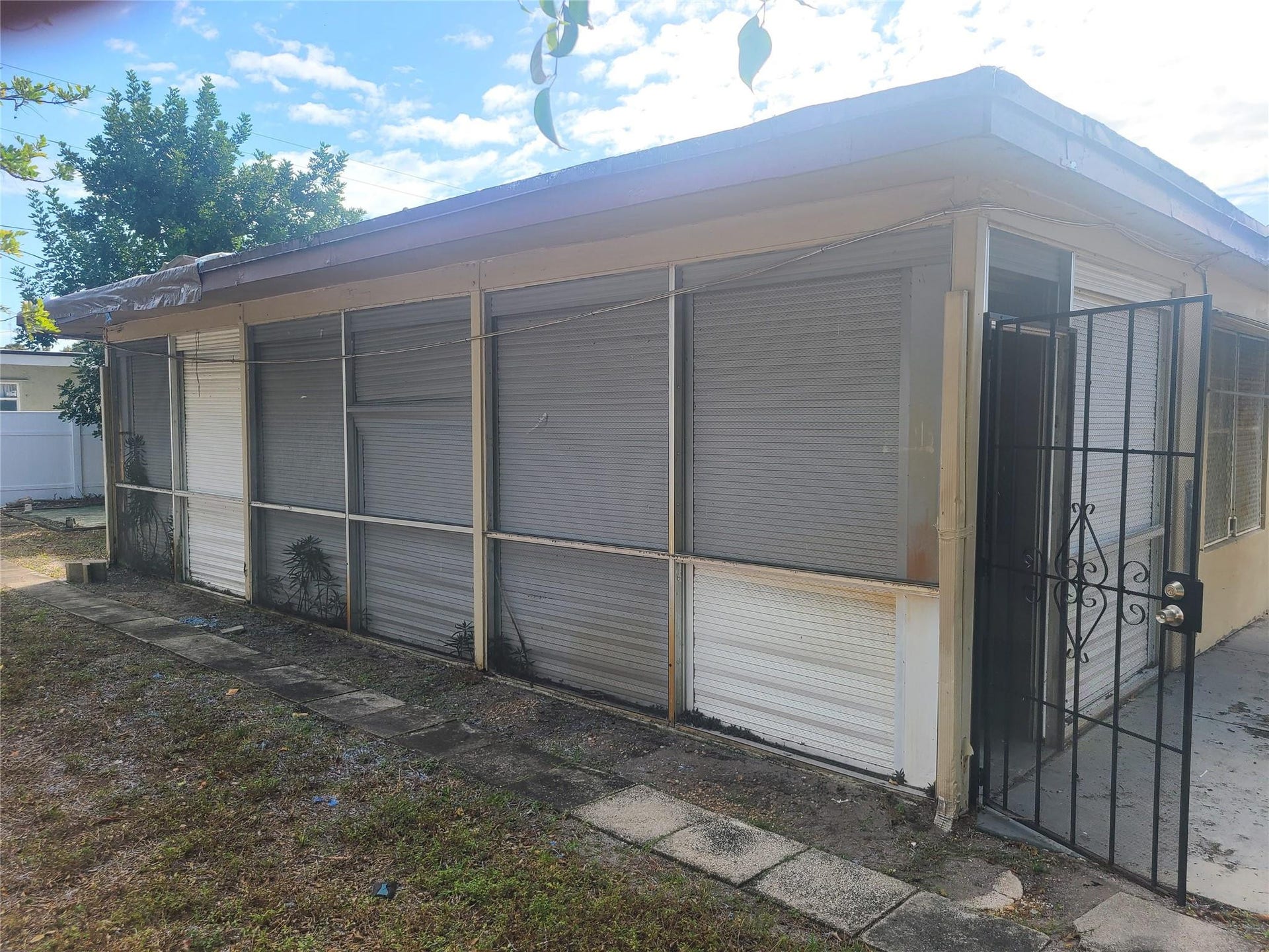 7757 SE EMBASSY Boulevard, Miramar, FL 33023 Screened enclosure with an ornate security gate and concrete tile path